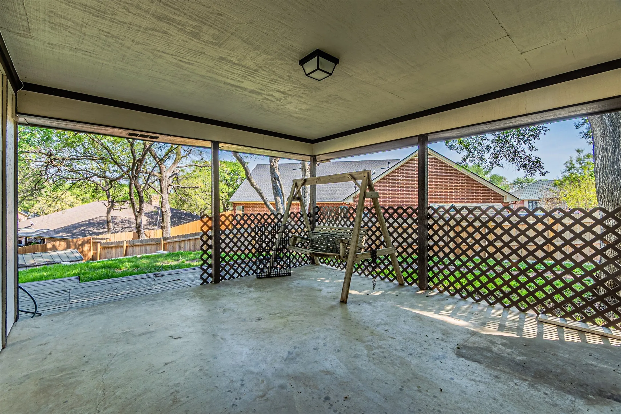 Expansive covered patio with concrete flooring, framed openings, and lattice screening