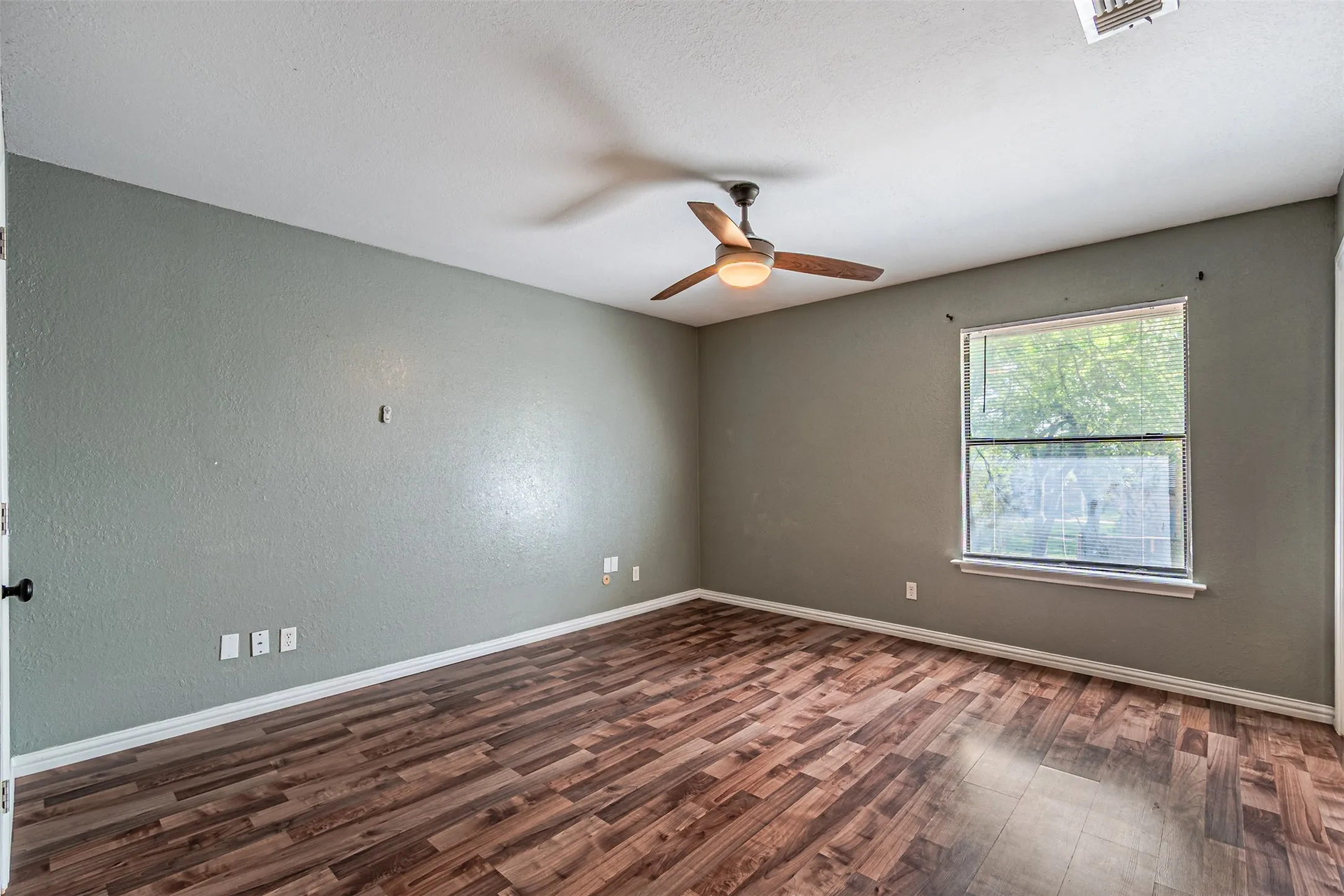 Wood-finish flooring, single window, ceiling fan, and painted walls