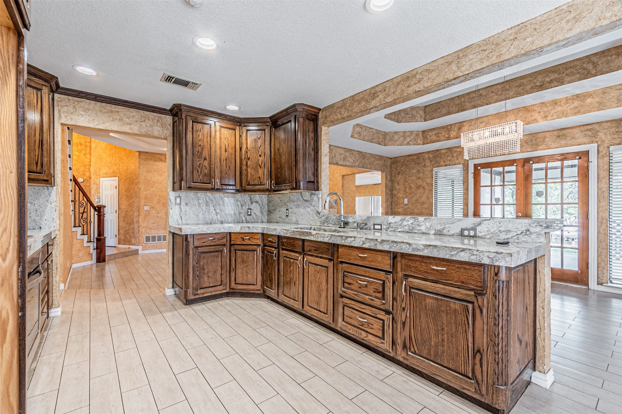 Kitchen featuring wood cabinetry, stone countertops, integrated sink, and recessed lighting