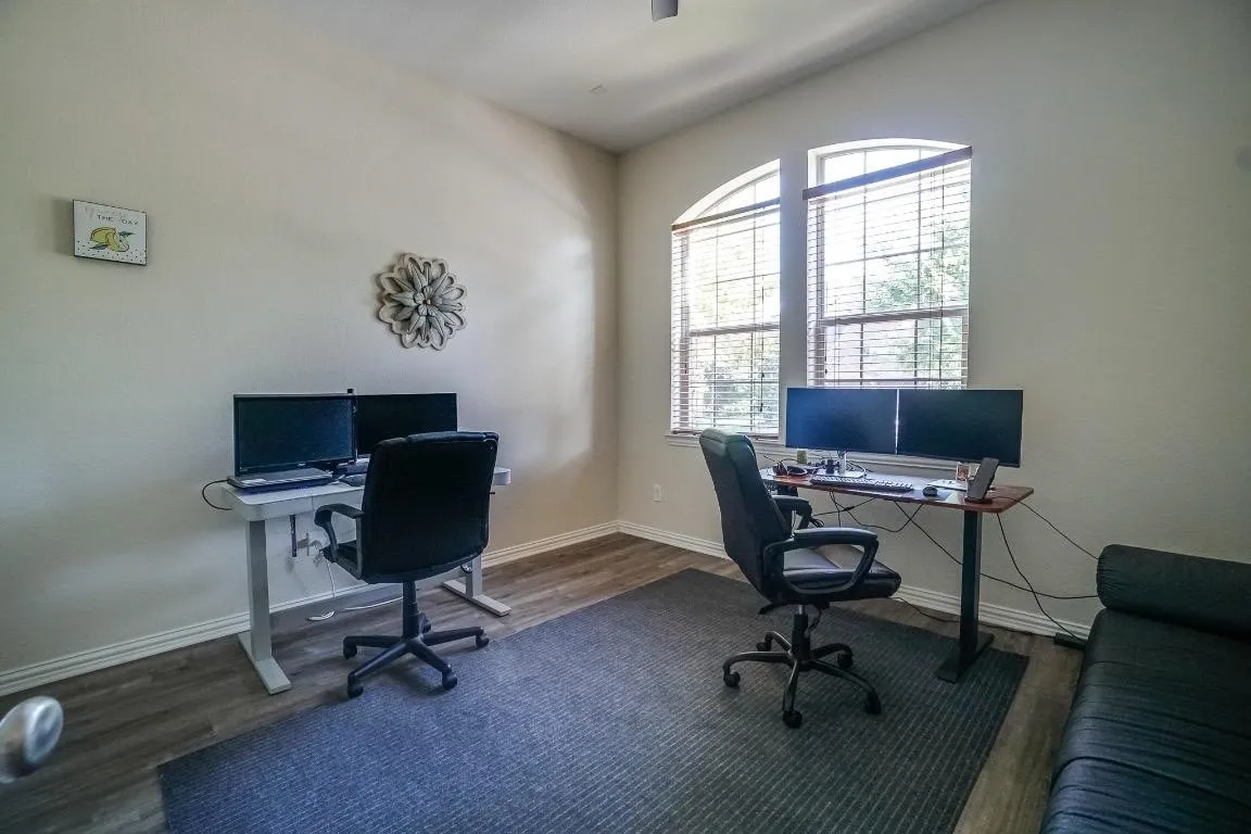 Room featuring vaulted ceilings, wood-finish flooring, and two arched windows with blinds