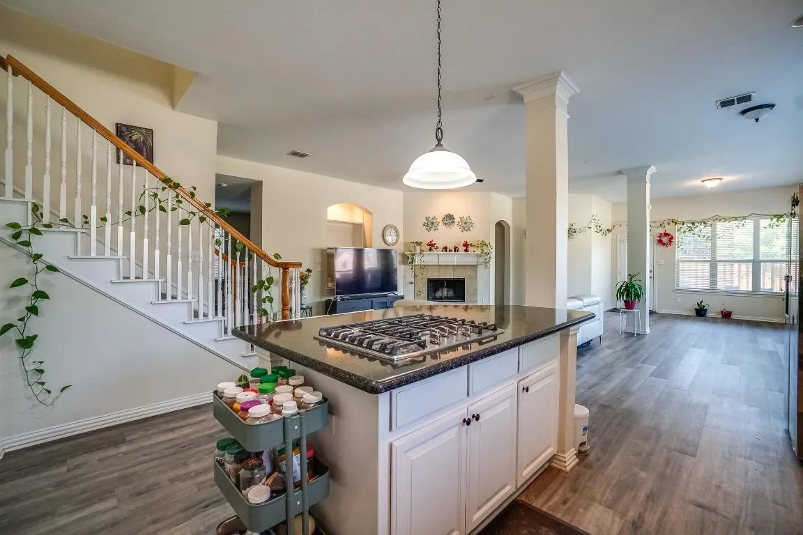 Kitchen island with a built-in gas range, granite-style countertop, and white cabinetry