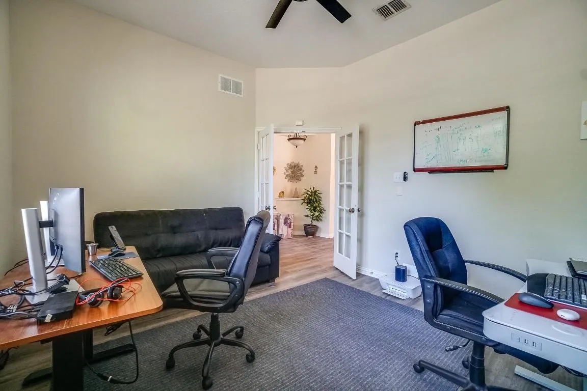 Vaulted ceiling, ceiling fan, wood-finish flooring, and French doors