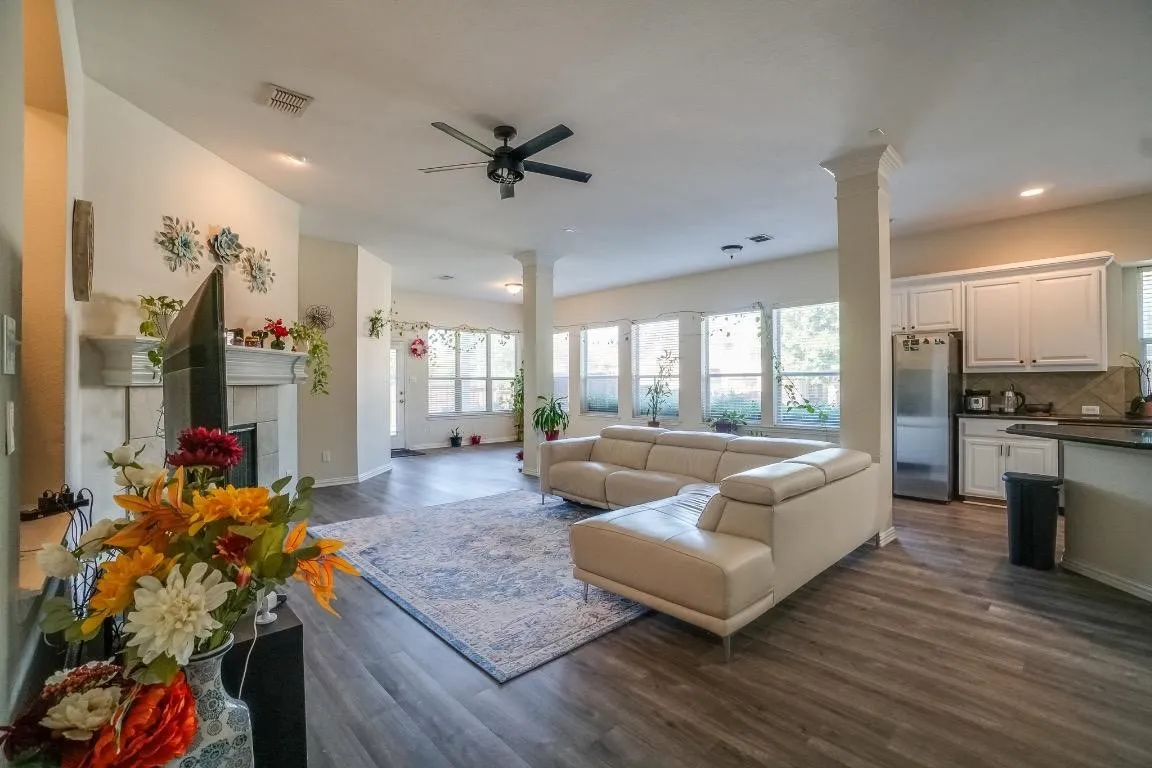 Open-concept living space featuring wood-finish flooring, a ceiling fan, and a fireplace with a mantel