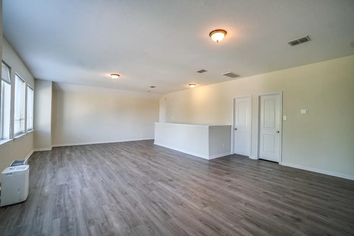 Open-concept room featuring wood-finish flooring, multiple windows, and a neutral color palette