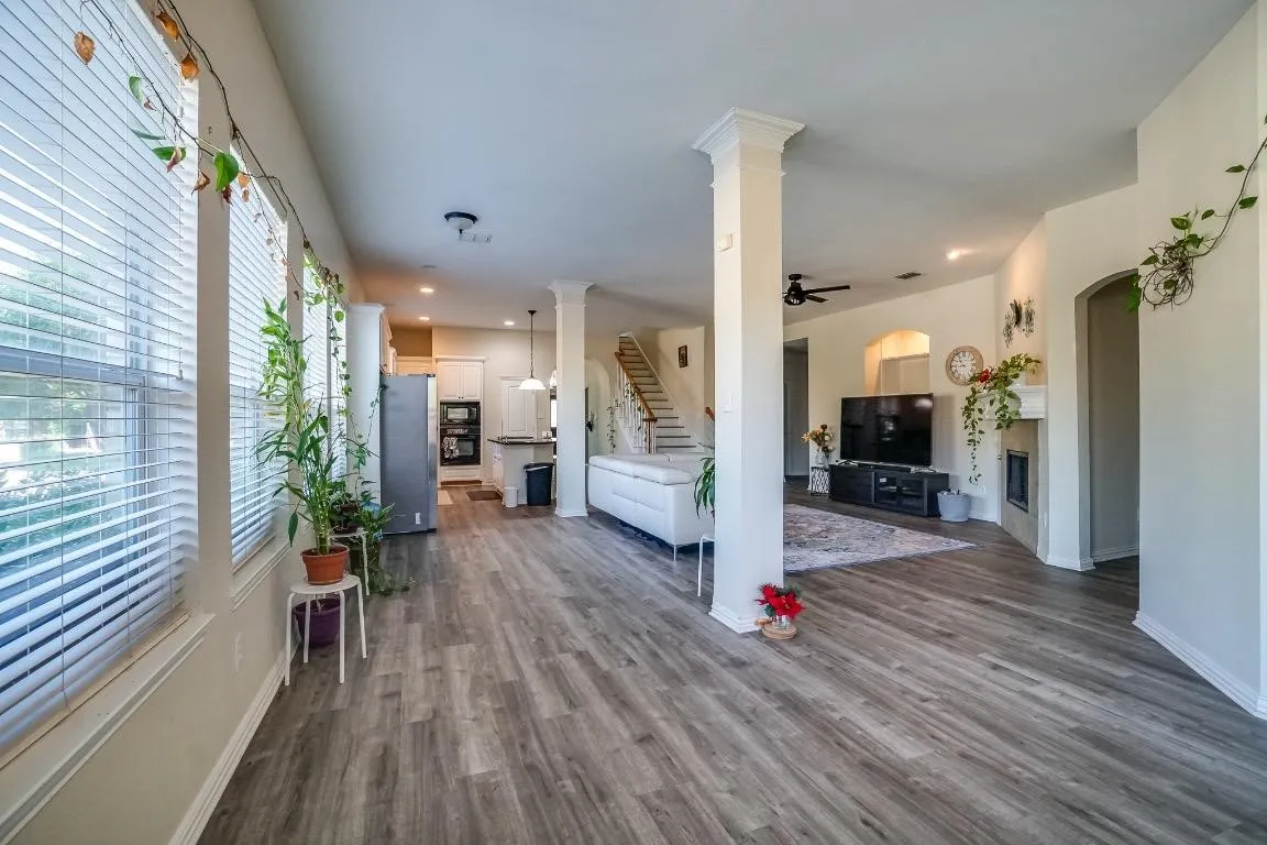 Expansive open-concept living area featuring wood-finish flooring, abundant natural light, recessed lighting, and a built-in fireplace