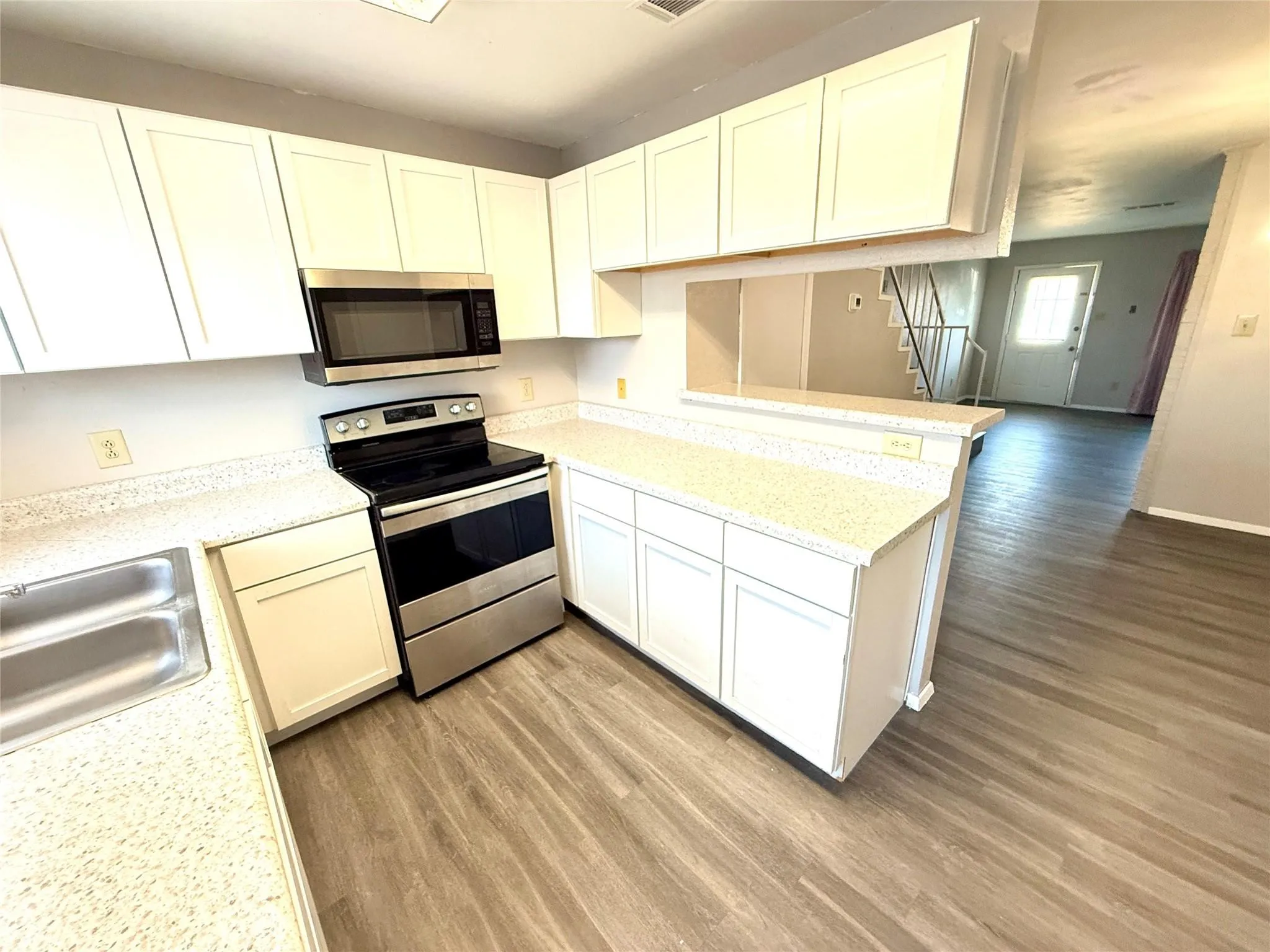 Kitchen featuring white cabinetry, light-toned countertops, a stainless steel oven/range, and a stainless steel microwave