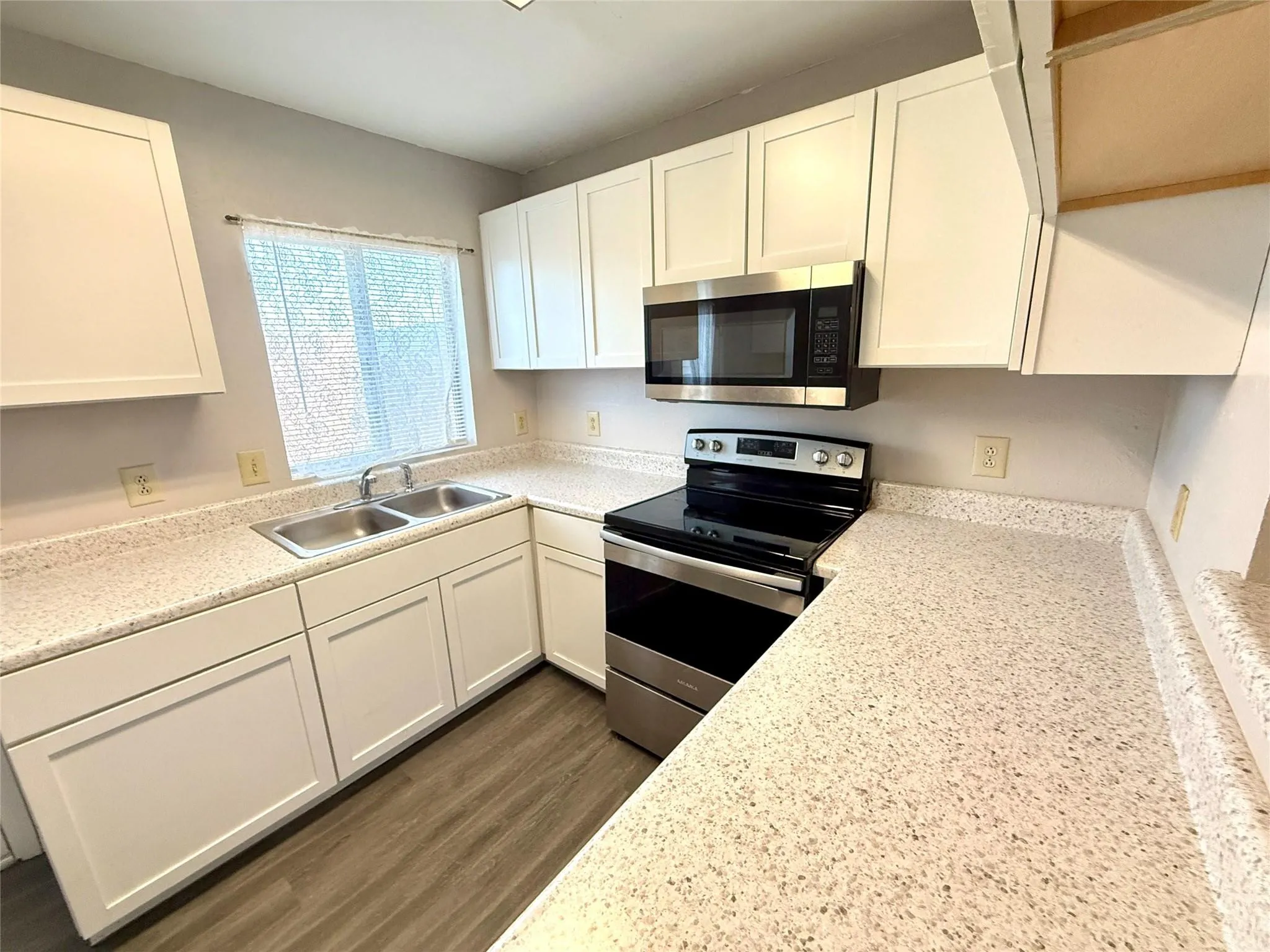 White cabinetry, dual basin stainless steel sink, over-the-range stainless steel microwave, and a black electric range with a stainless steel finish