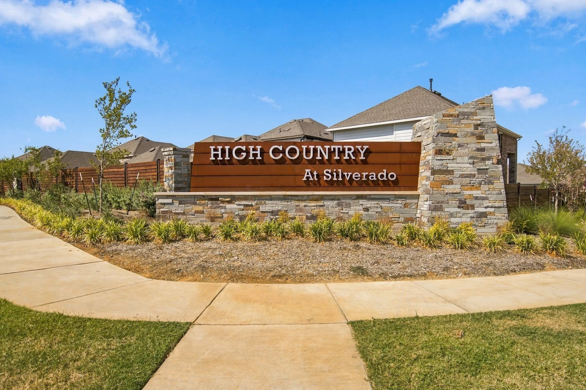 Stone veneer monument sign featuring wood-finish paneling and integrated lettering