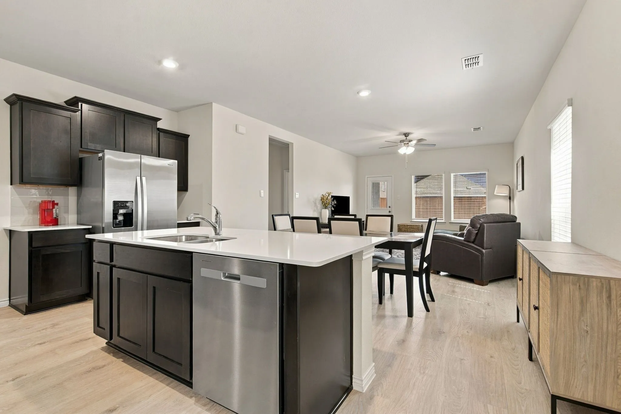 Kitchen featuring dark wood cabinetry, white countertops, stainless steel appliances, and wood-finish flooring