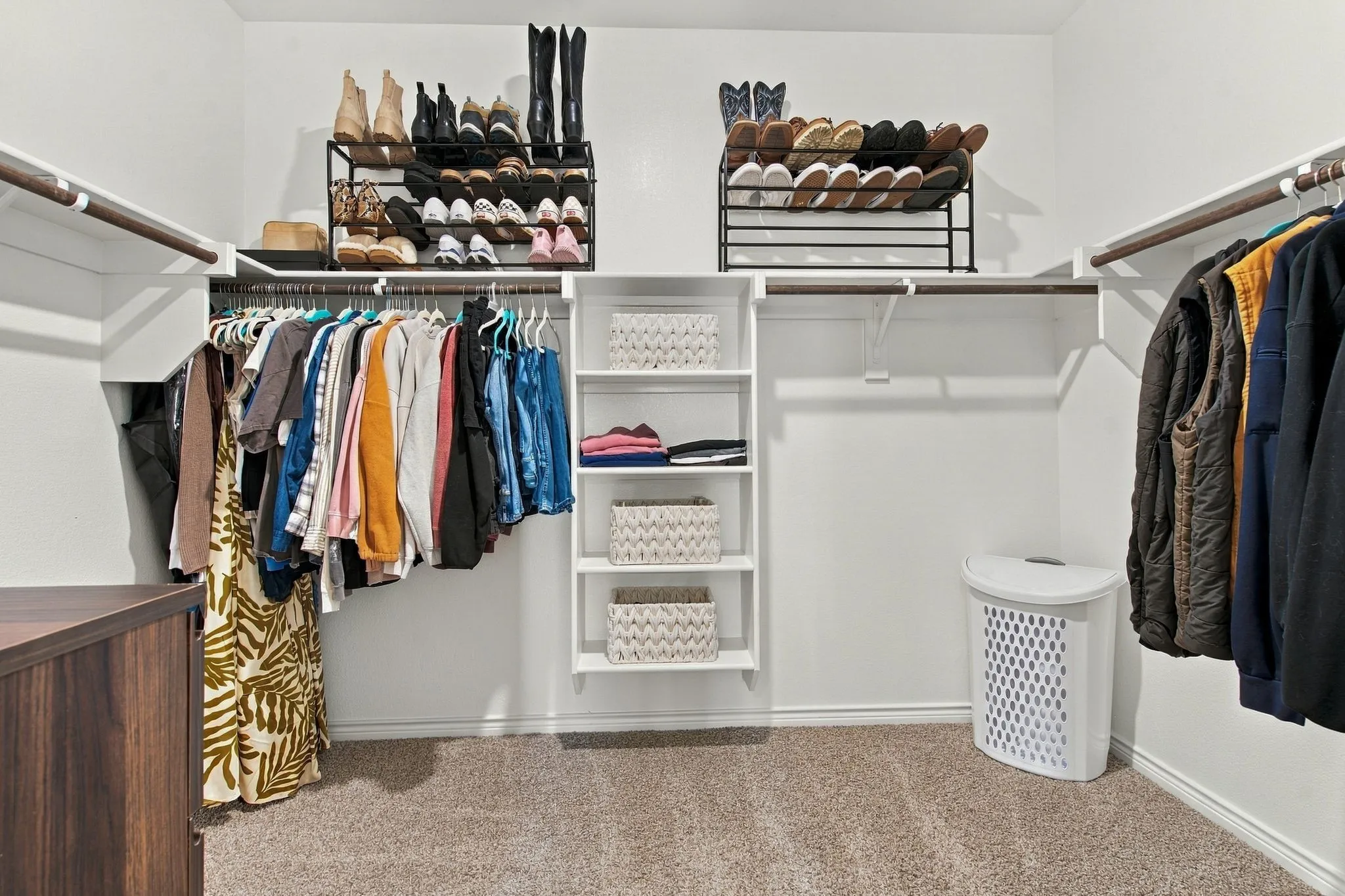 Large Primary closet with built-in shelving, hanging rods, and carpet flooring within a white-painted interior