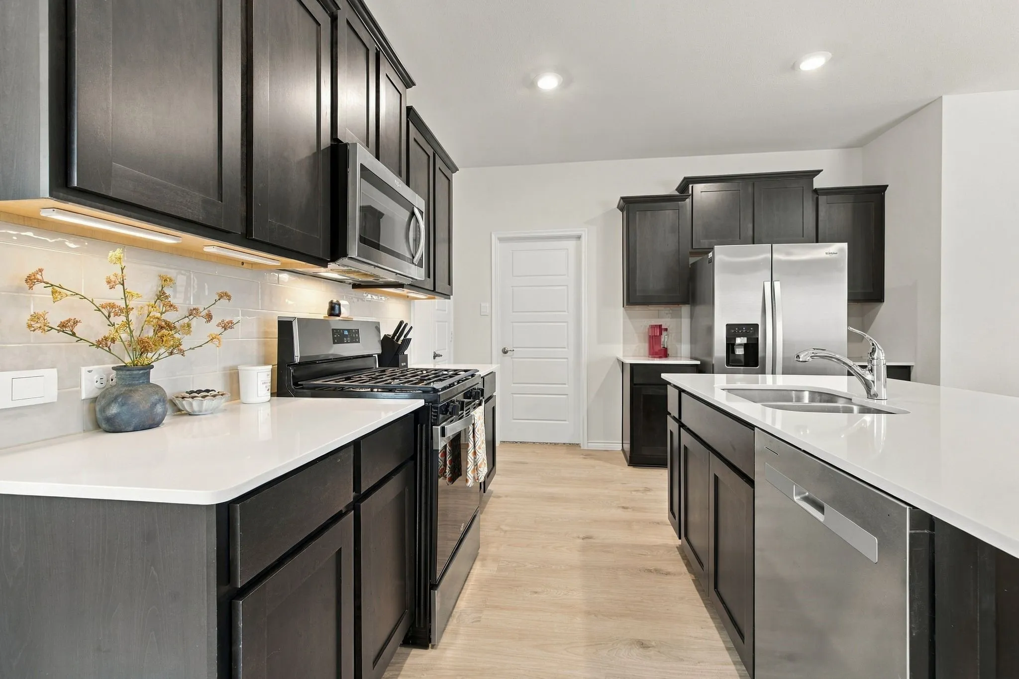 Island,quartz countertop, built in microwave, a tiled backsplash, and wood-finish flooring