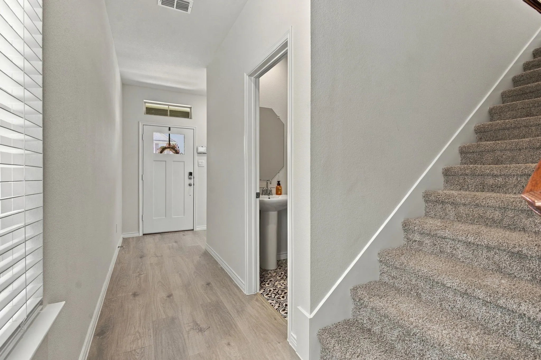 Entryway with storage closet, wood-finish flooring, and a white paneled door with transom window