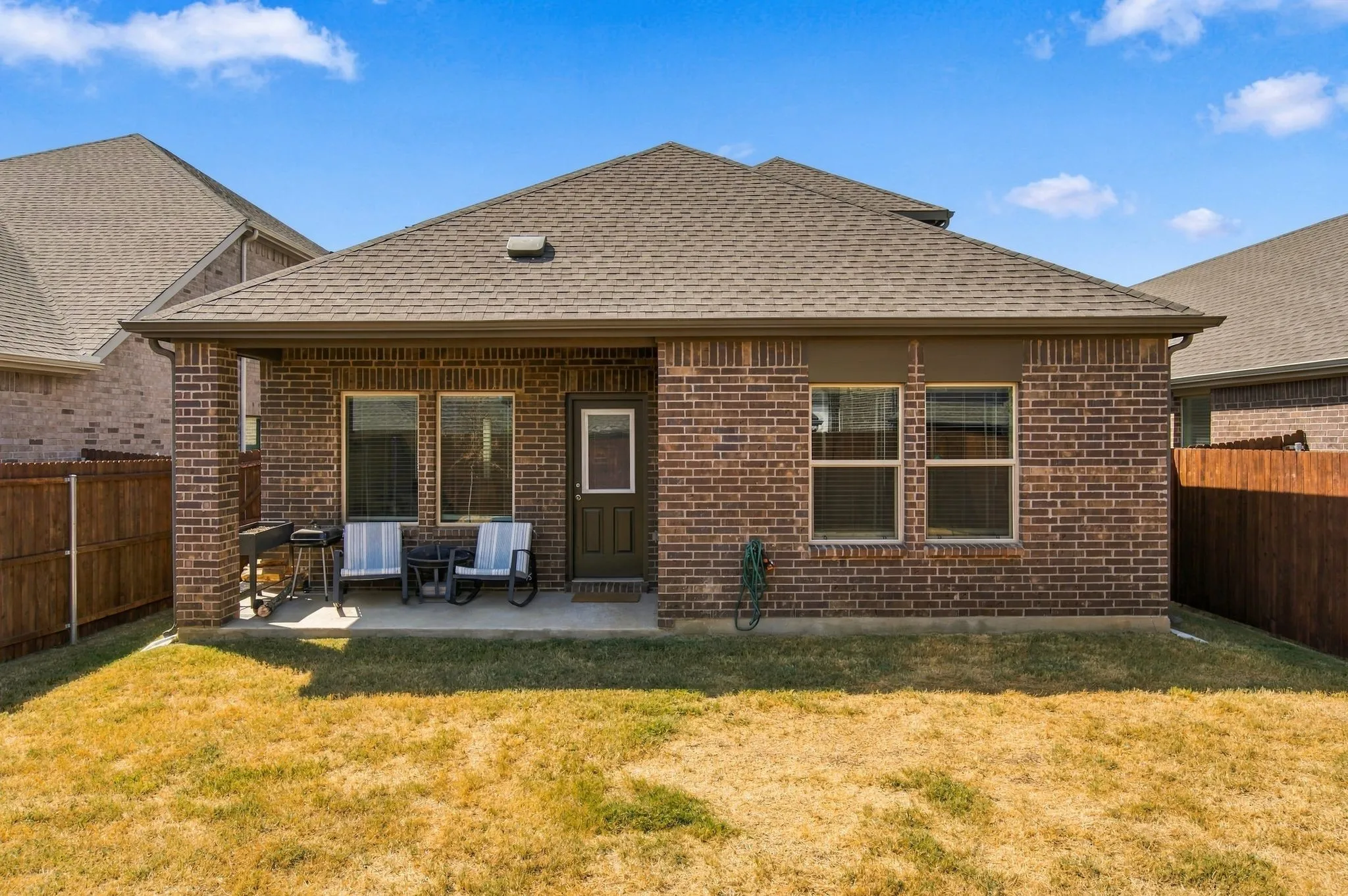 Brick exterior with a covered patio and gutters overlooking a spacious backyard