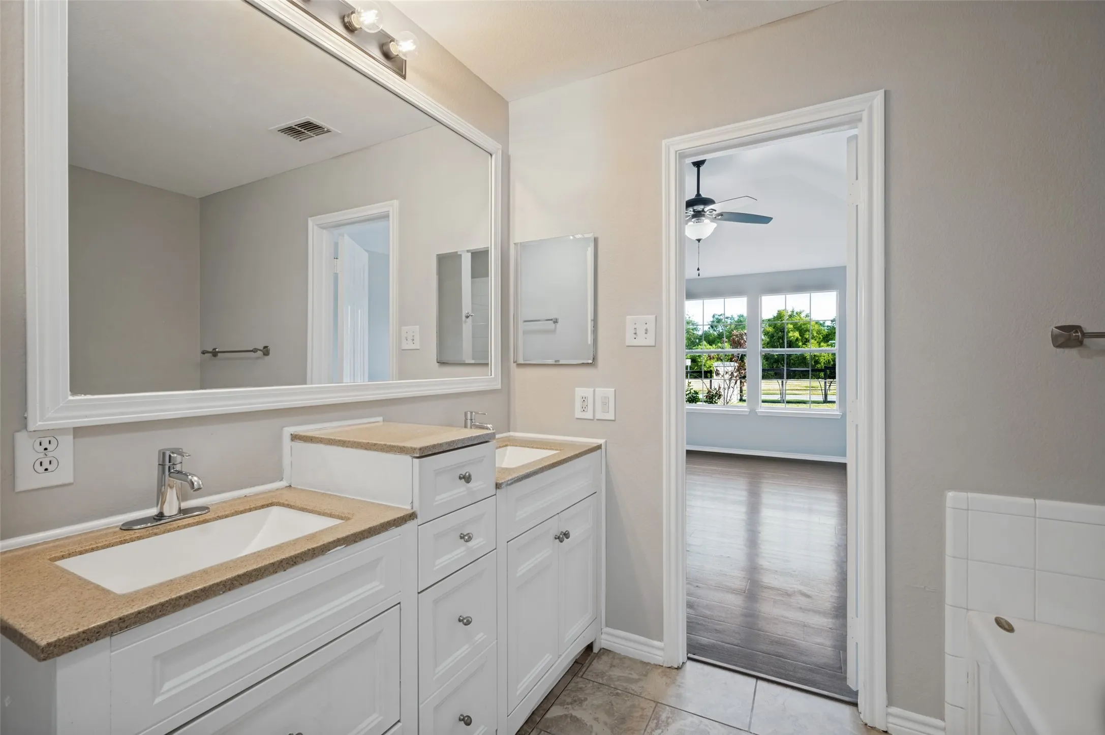 Dual vanity with white cabinetry, integrated sinks, and neutral countertops