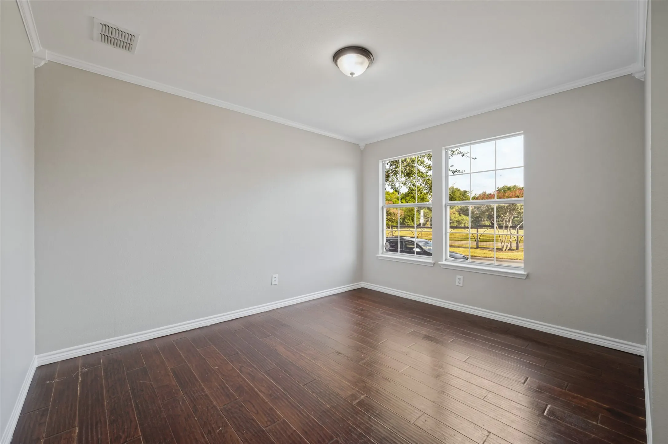Wood-finish flooring, white window trim, dual windows, and crown molding
