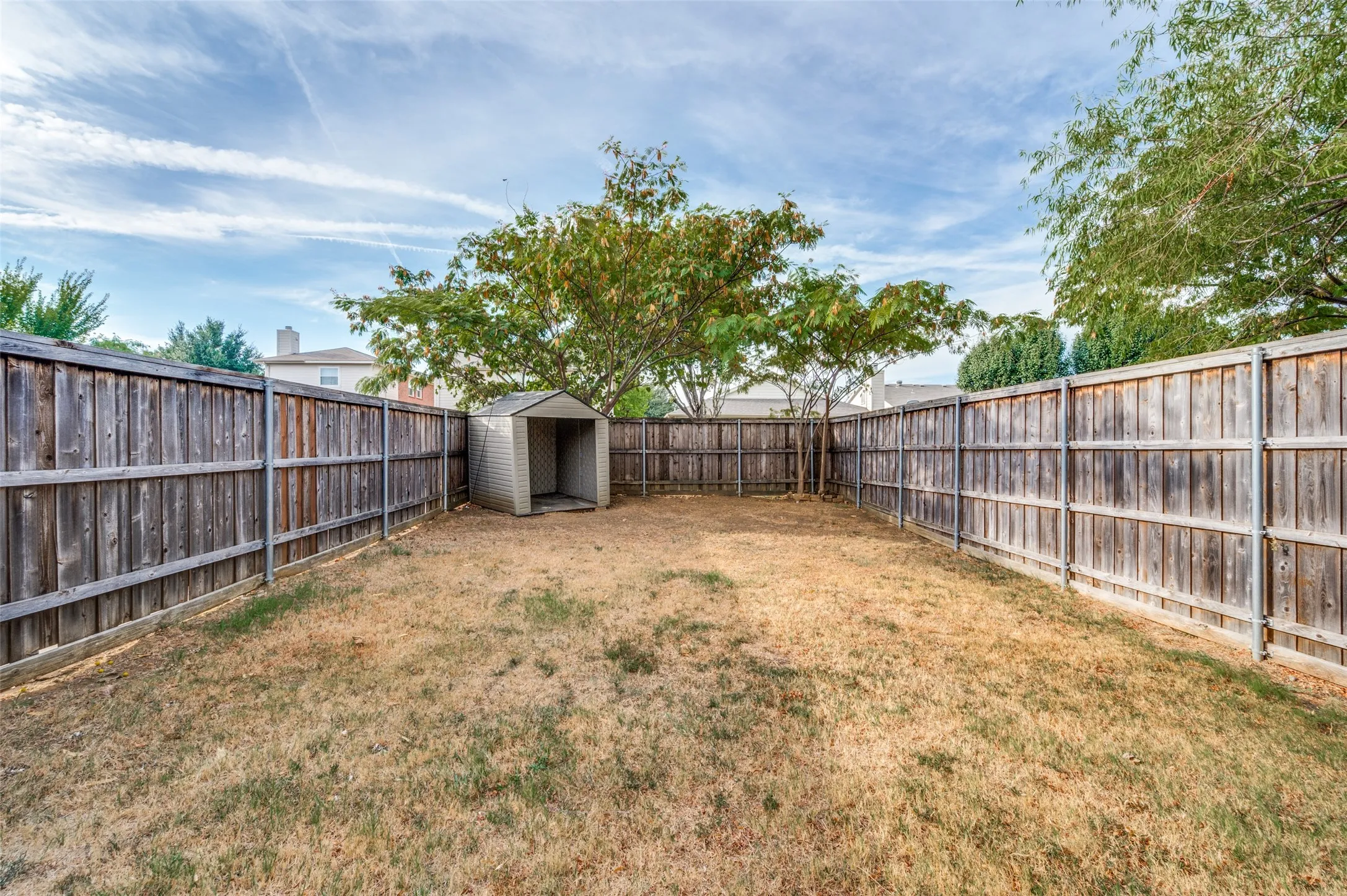 Fully fenced backyard with a storage shed