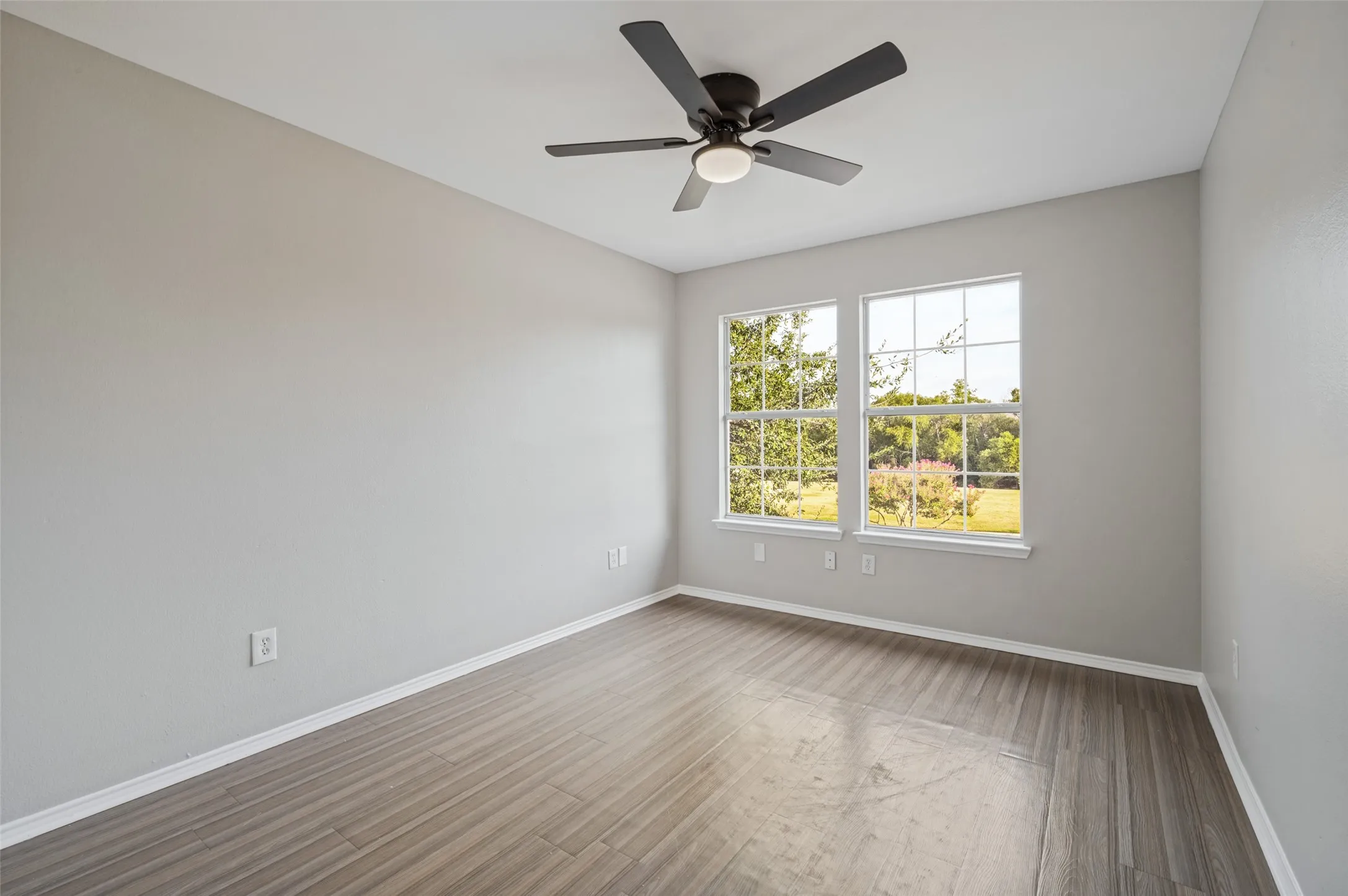 Wood-finish flooring, dual windows, and a ceiling fan with integrated lighting