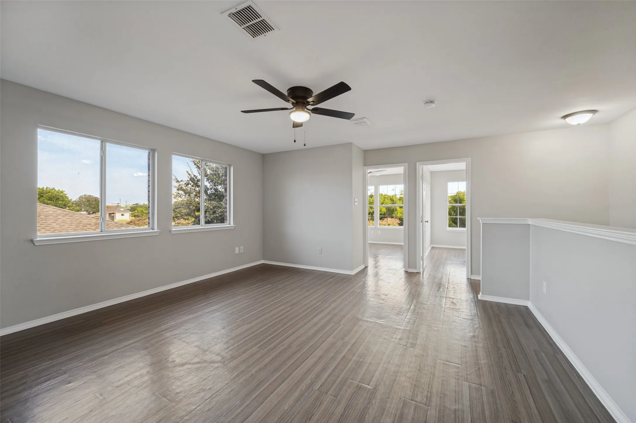 Spacious room featuring wood-finish flooring, multiple windows, a ceiling fan, and recessed lighting