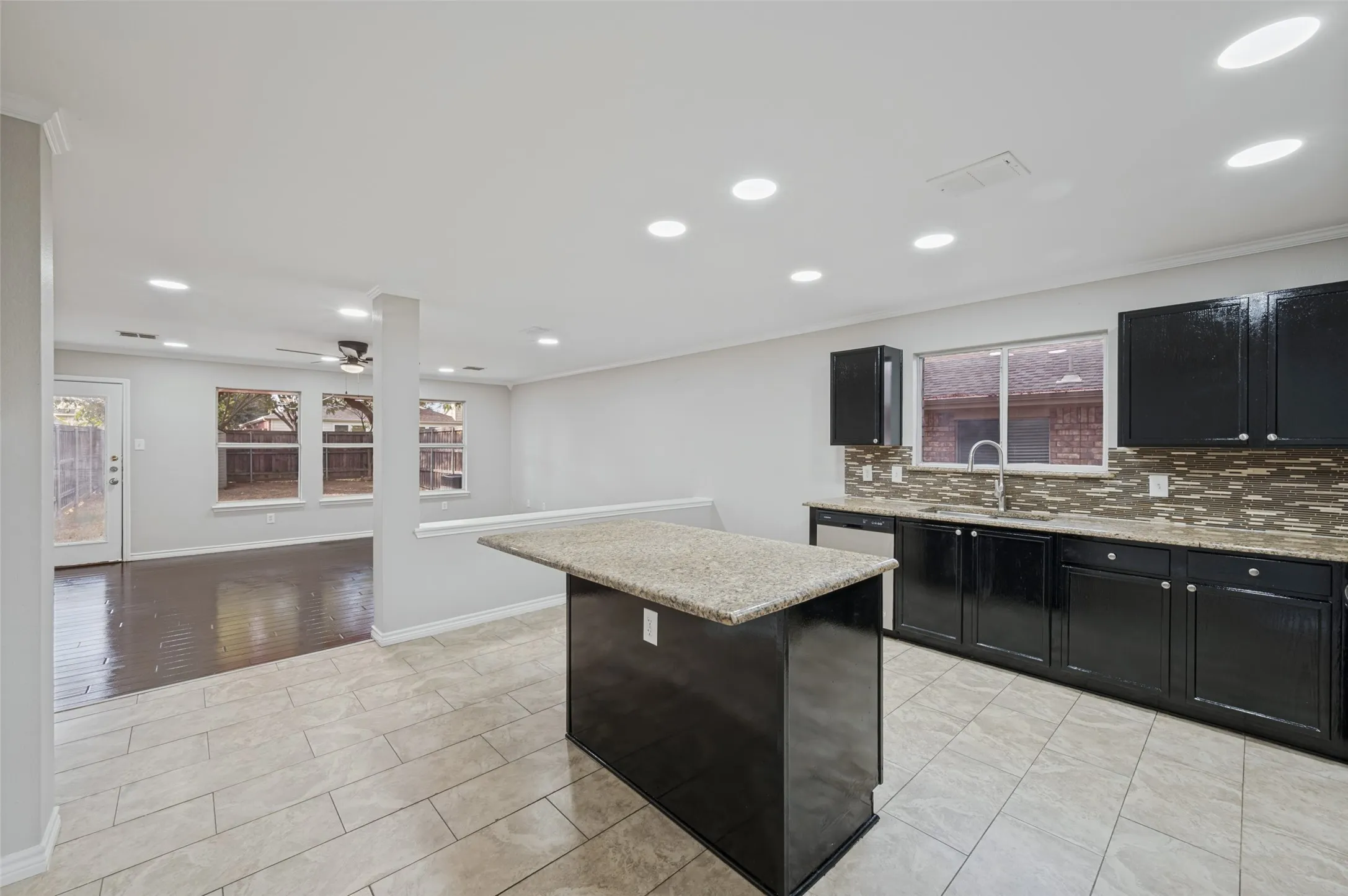 Kitchen features black cabinetry with a tiled backsplash and light-toned countertops
