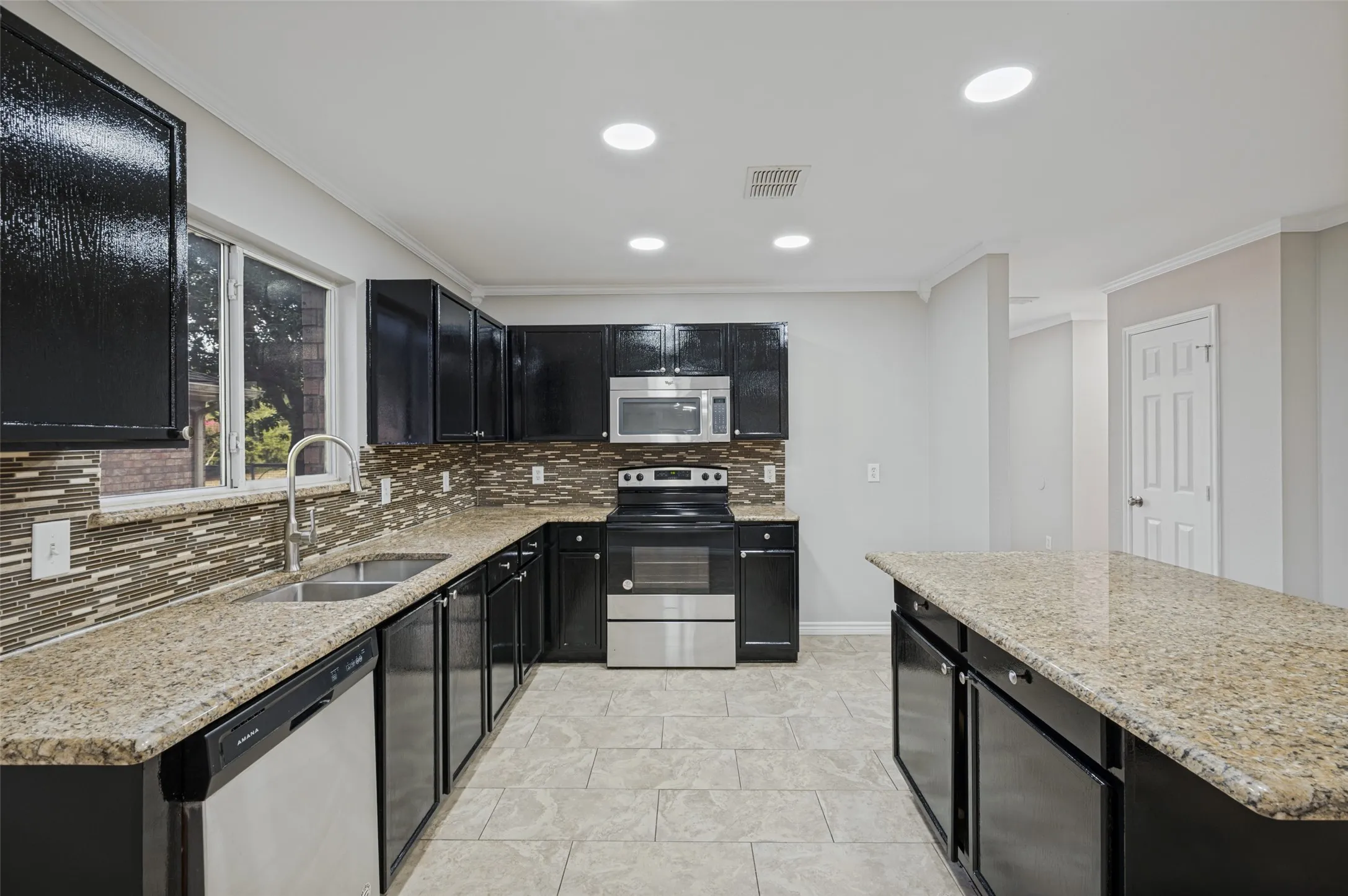Kitchen featuring extensive cabinetry, stone countertops, stainless steel appliances, a tile backsplash, and recessed lighting