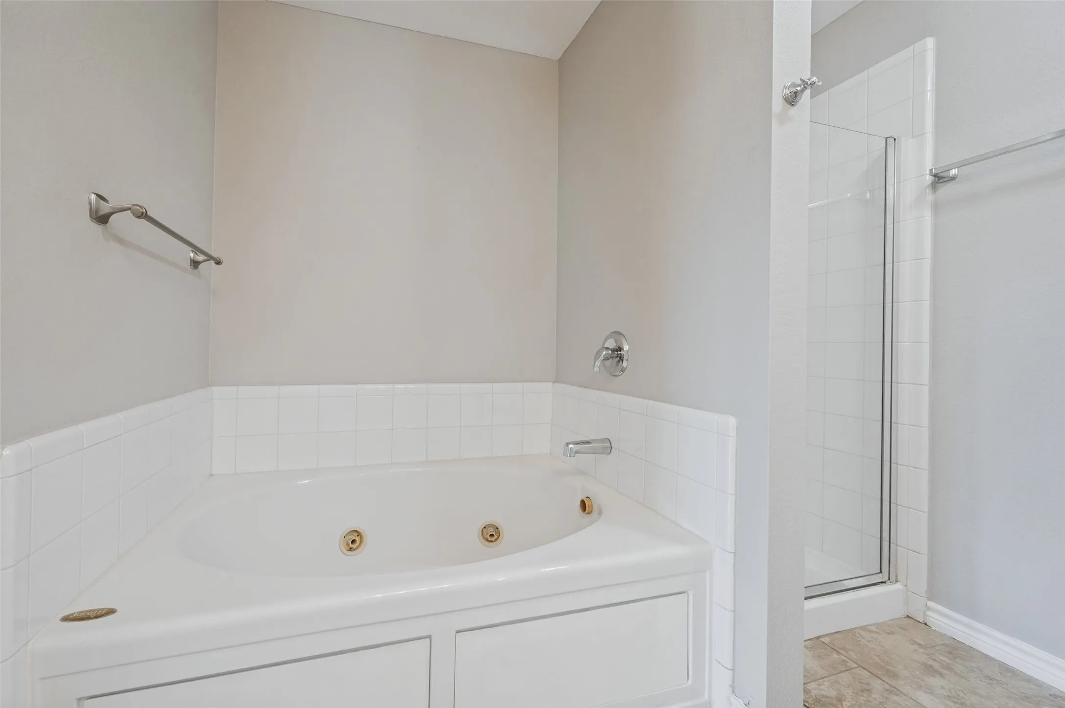 Corner soaking tub with jets, white subway tile surround, and a clear glass shower enclosure