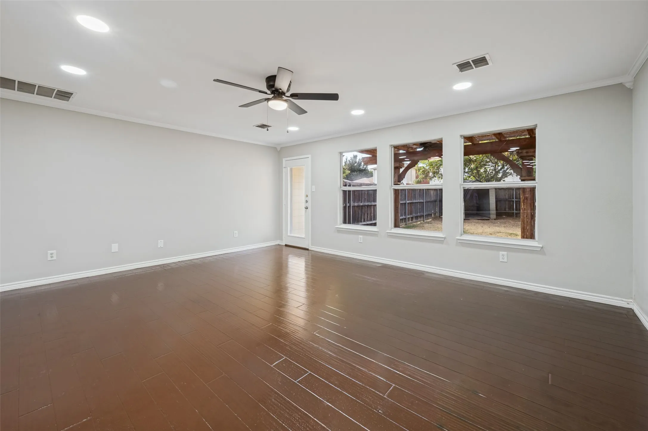 Recessed ceiling lighting, dark wood-finish flooring, ceiling fan, crown molding, and multiple windows