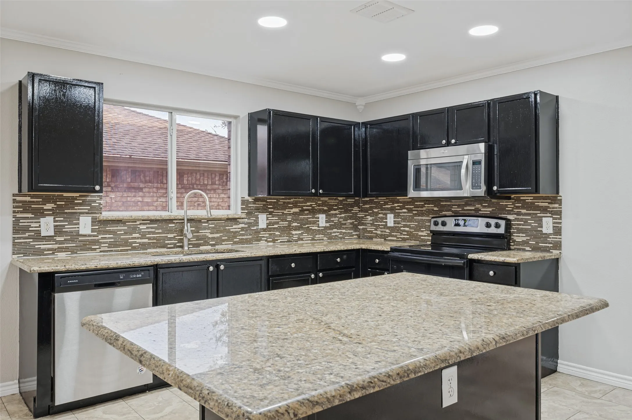 Kitchen featuring an island, black cabinetry, tile backsplash, recessed lighting, and stainless steel appliances