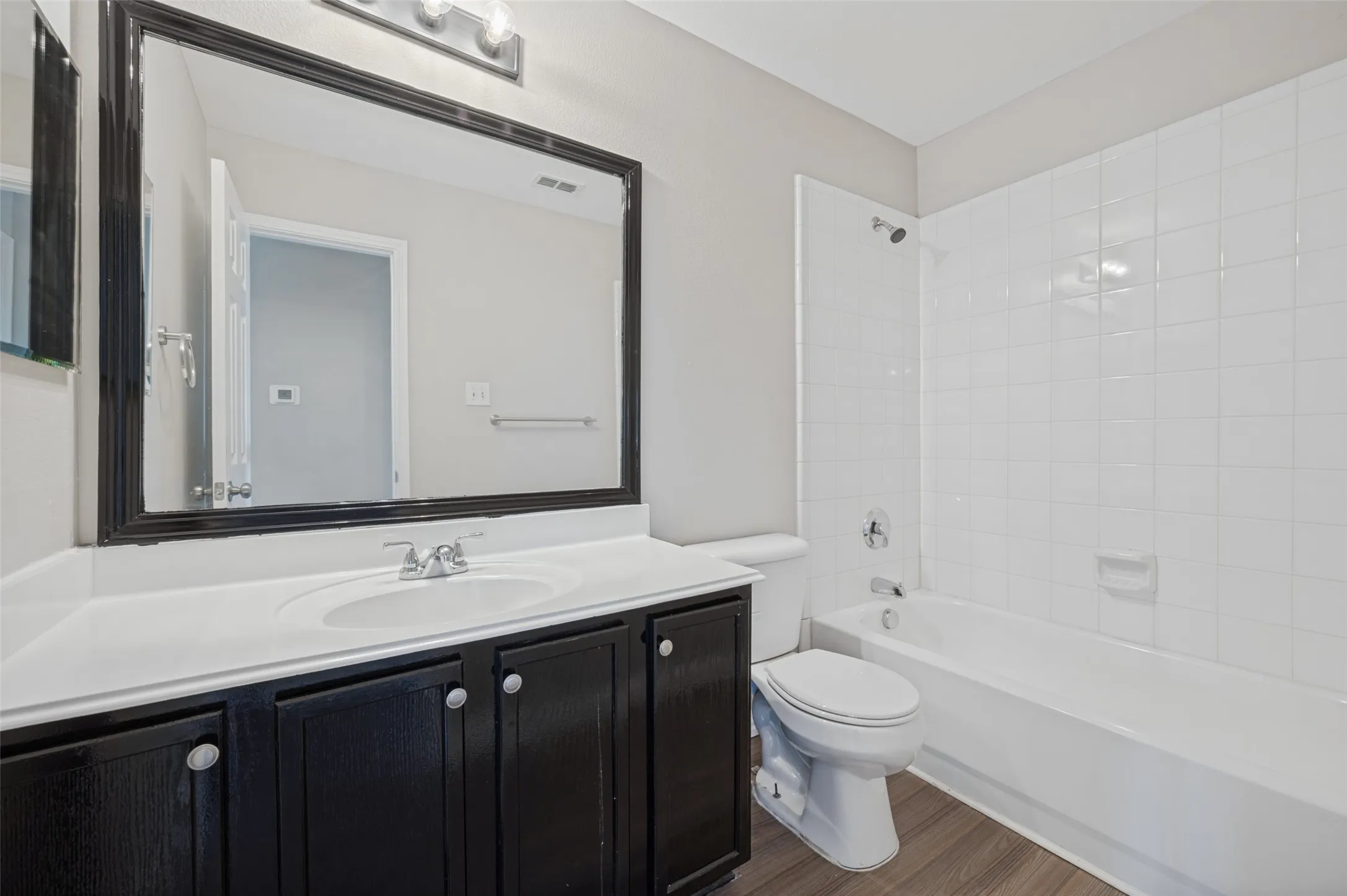 Vanity with black wood-finish cabinetry, white countertop, and integrated sink