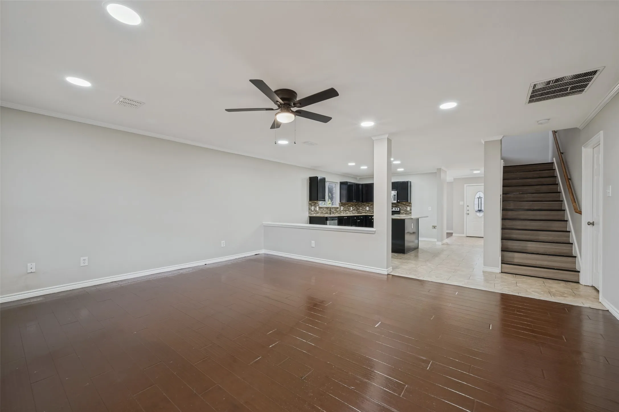 Recessed lighting, wood-finish flooring, ceiling fan, open-concept living, and staircase