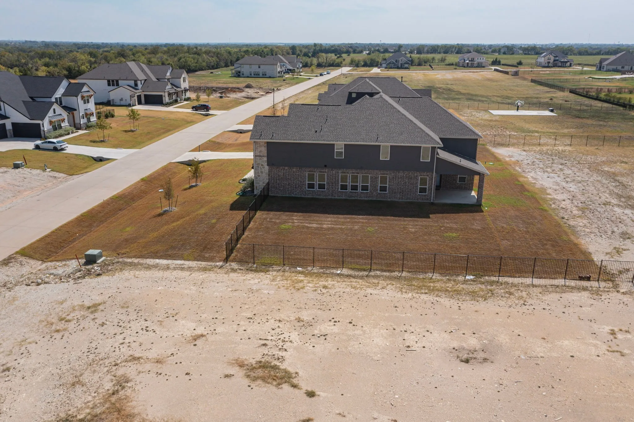 Two-story property featuring a stone and siding exterior, a covered patio, and a fenced backyard