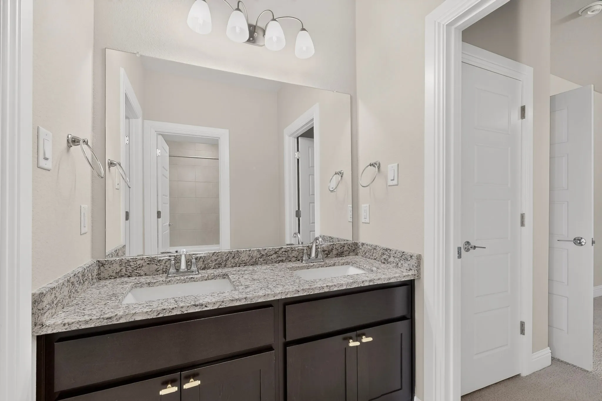 Dual vanity with undermount sinks, granite countertop, and dark wood-finish cabinetry