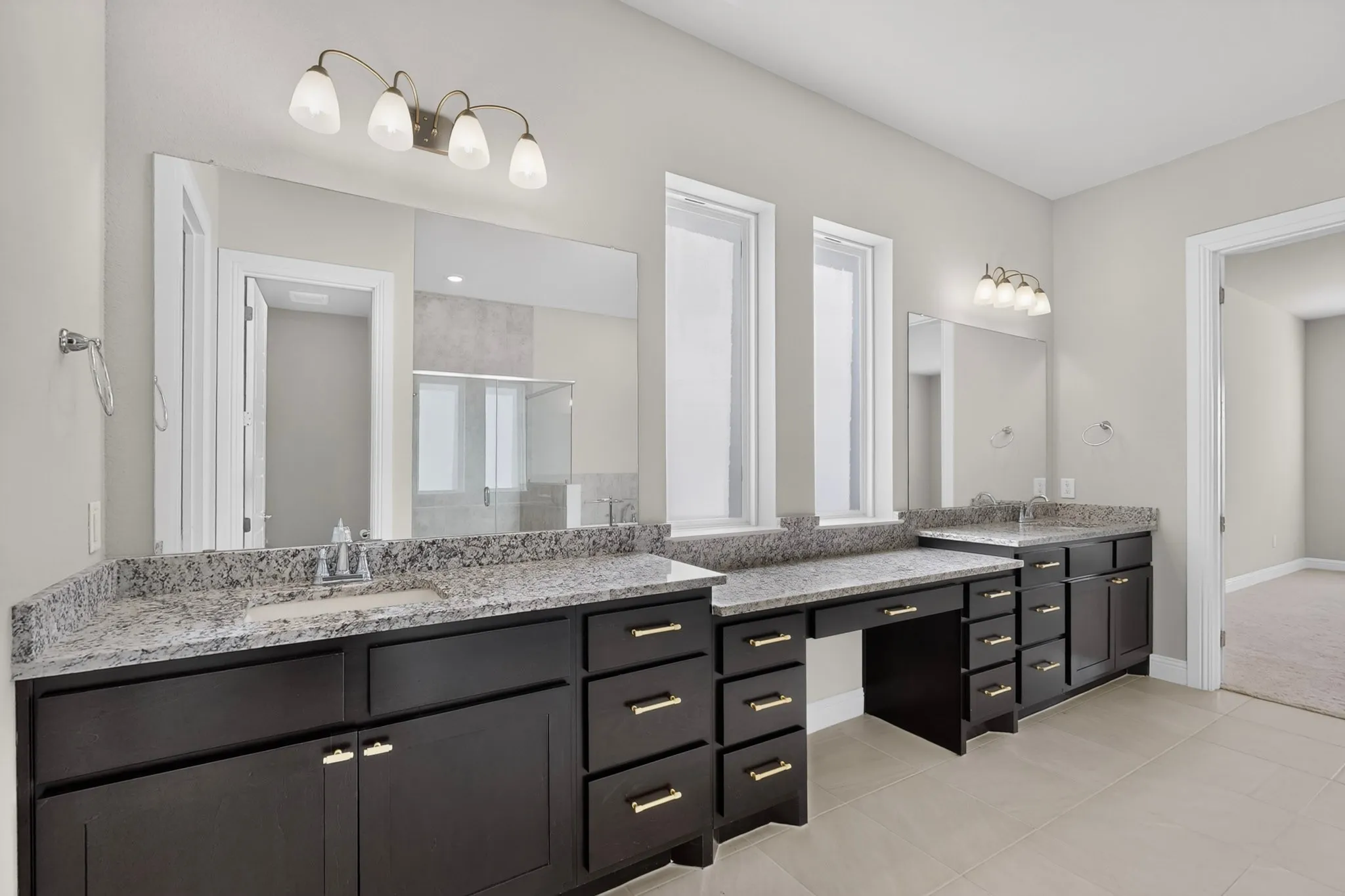 Dual vanities with undermount sinks, granite countertops, dark wood-finish cabinetry, and contemporary lighting fixtures