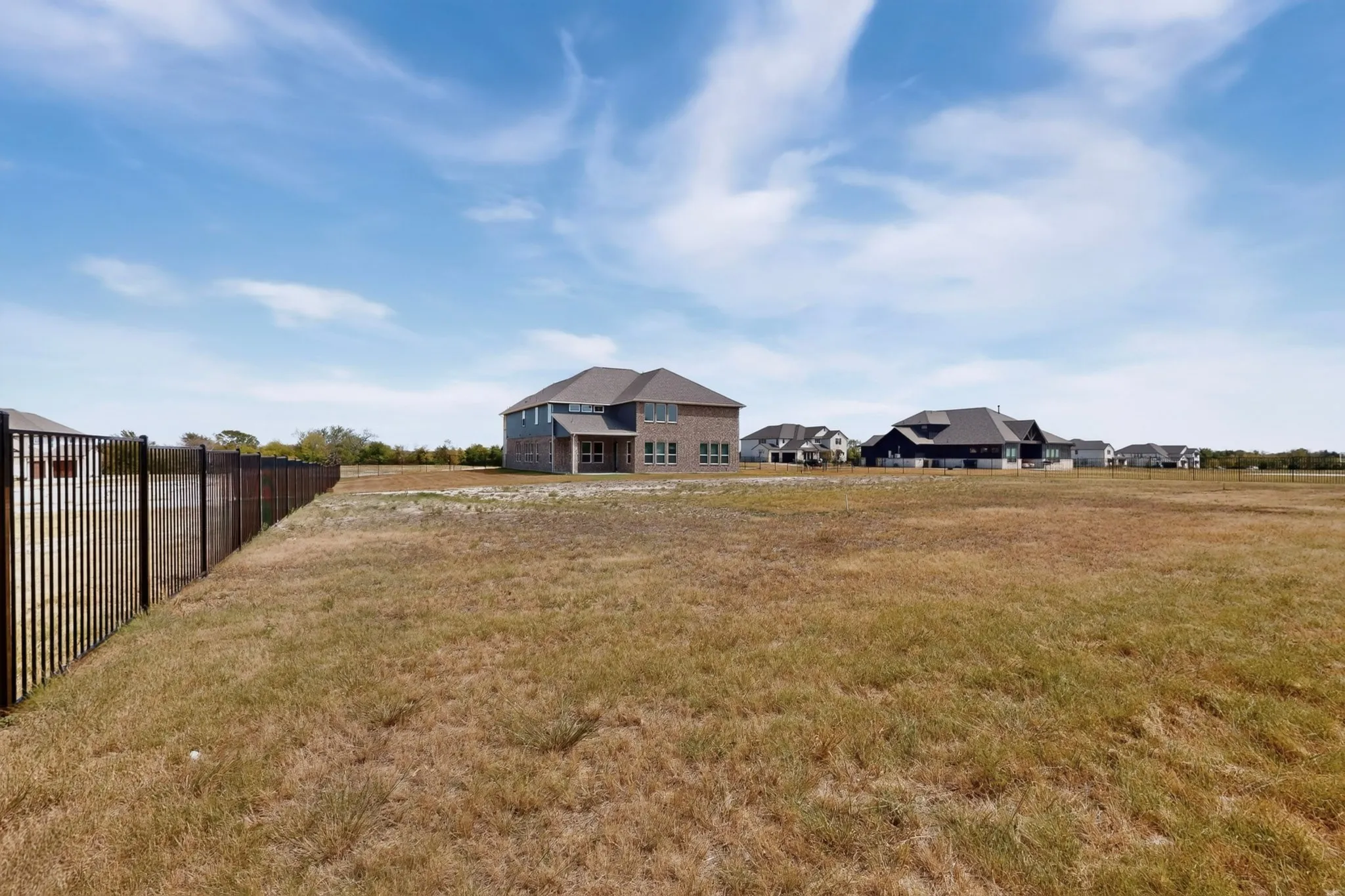 Expansive undeveloped land with a partial black metal fence