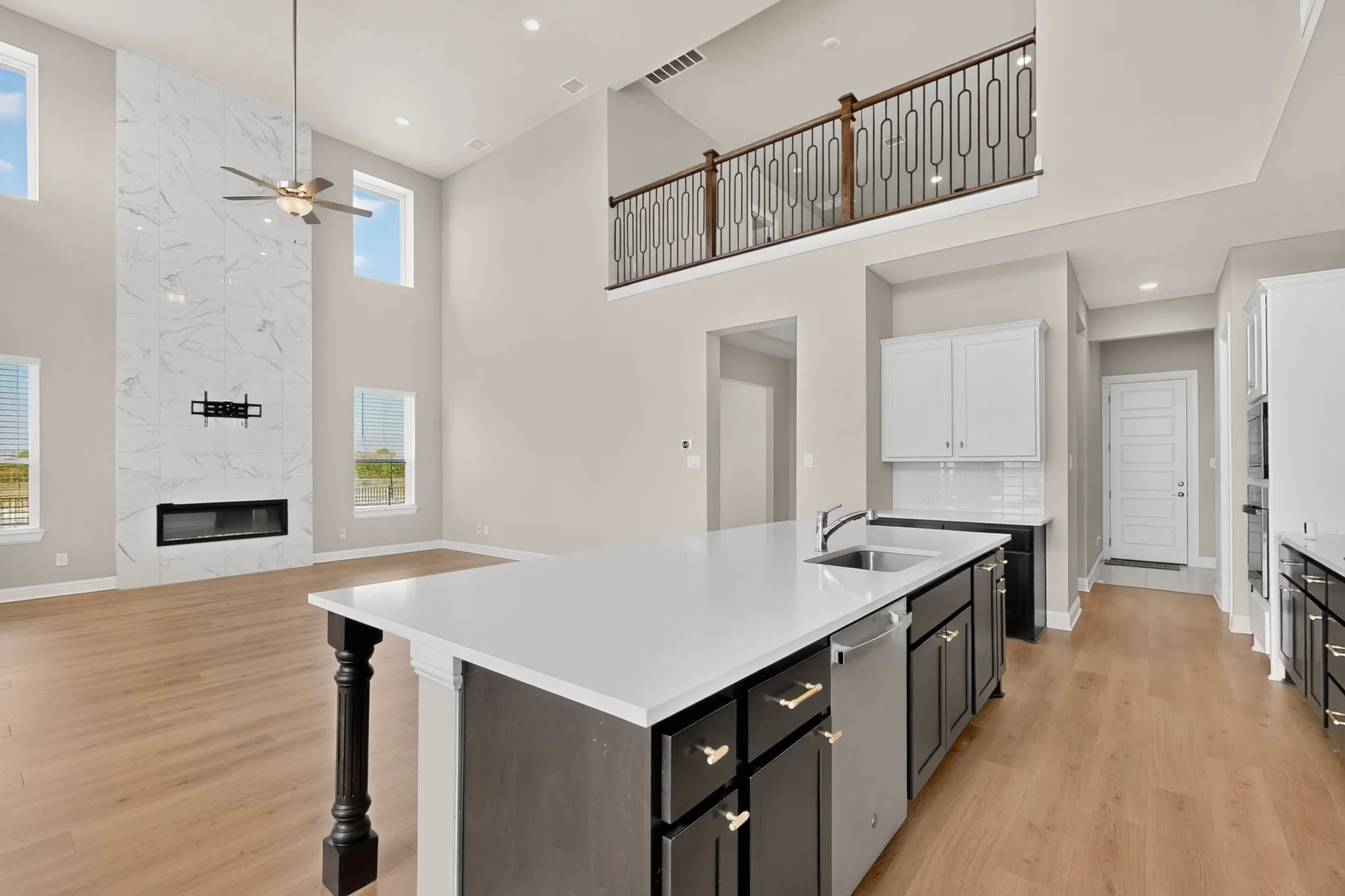 Expansive living area with a two-story ceiling, large format tile fireplace surround, and wood-finish flooring