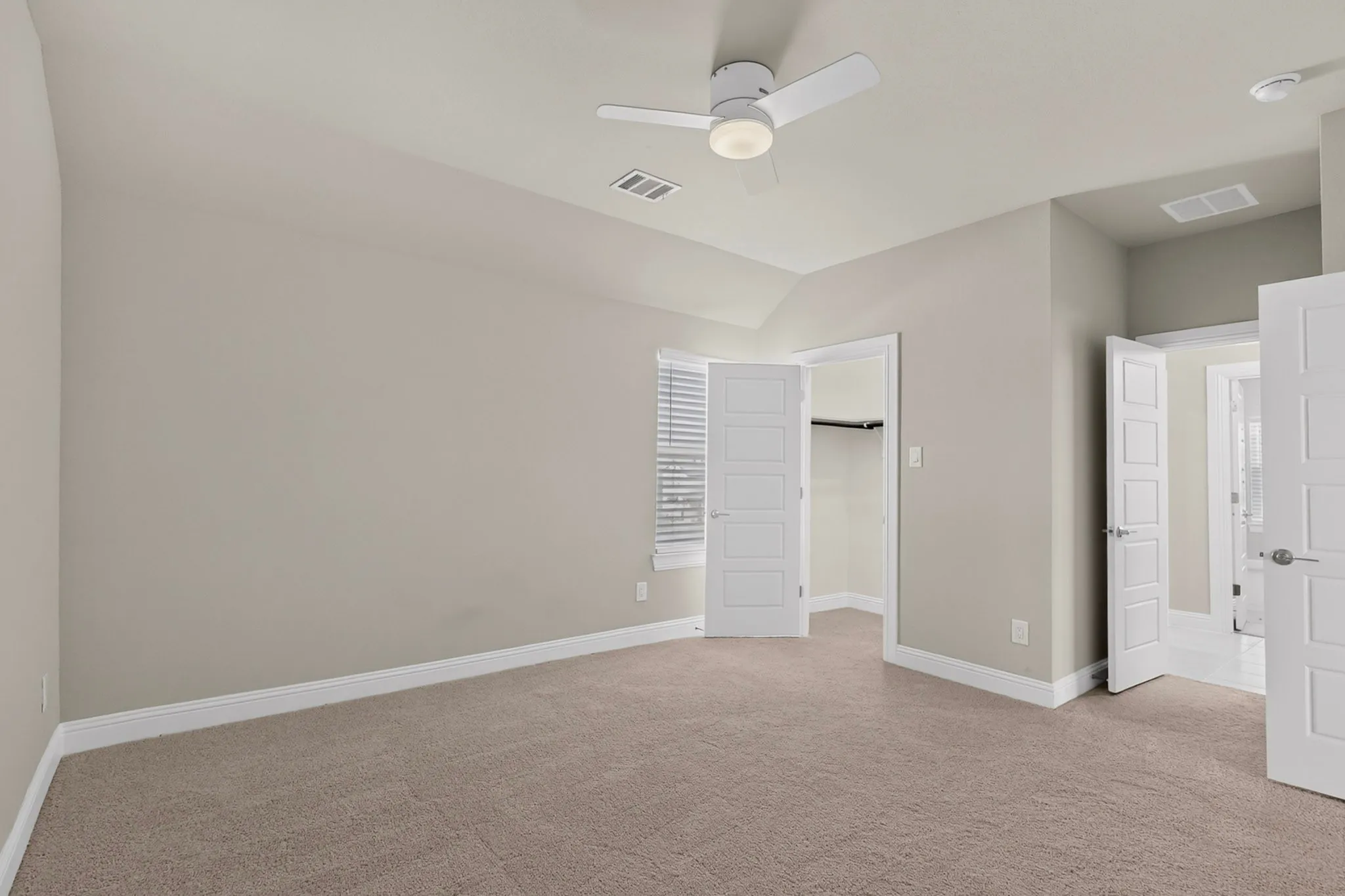 Neutral-toned carpeting, white trim, and a ceiling fan with integrated lighting