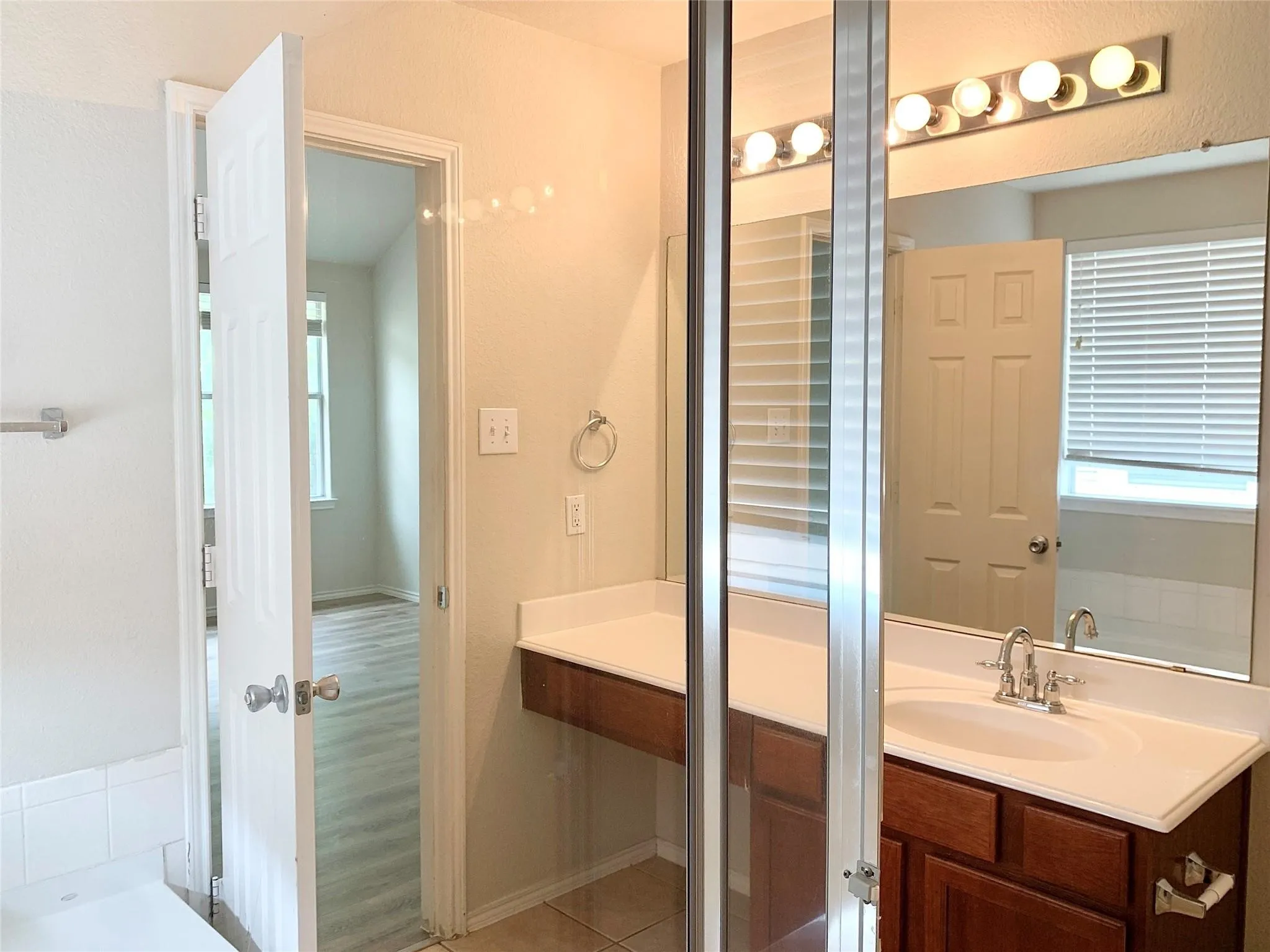 Vanity with a white countertop and integrated sink, chrome faucet, and a wall-mounted light fixture with multiple bulbs