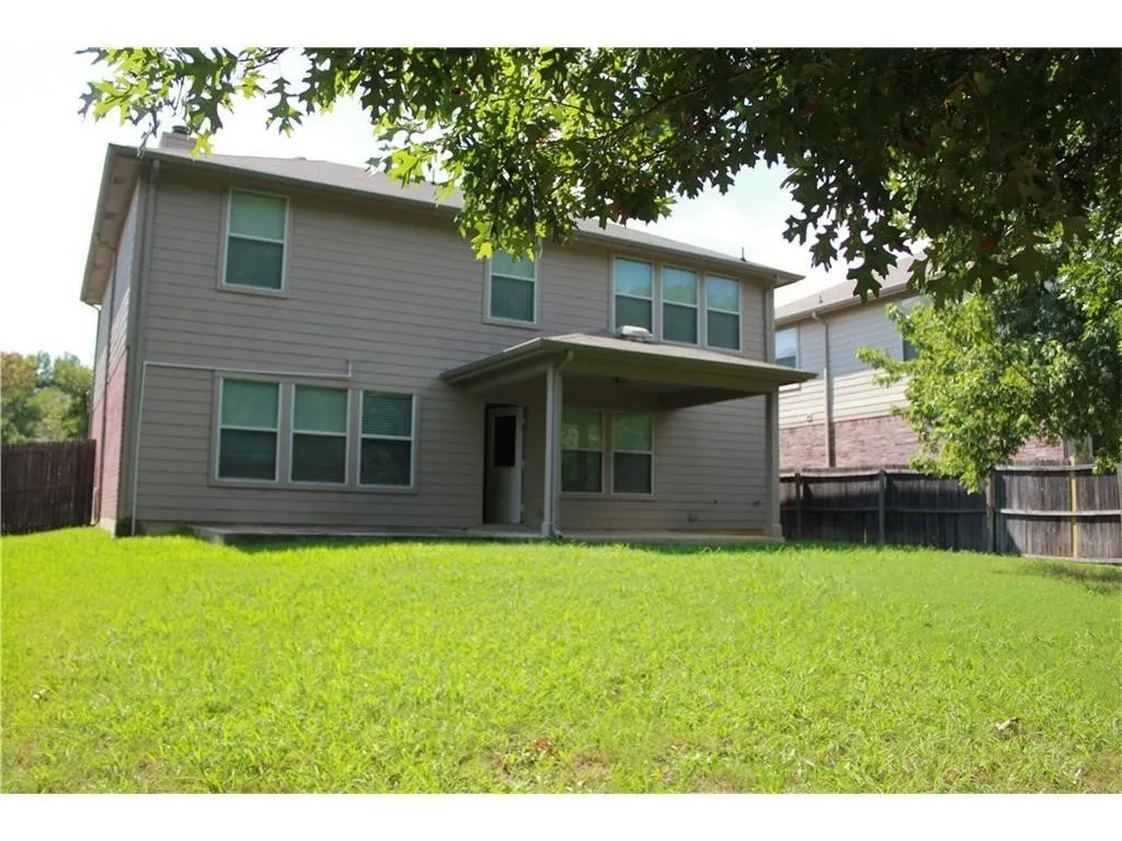 Two-story exterior with horizontal siding, multiple windows, a covered patio, and a spacious grassy yard