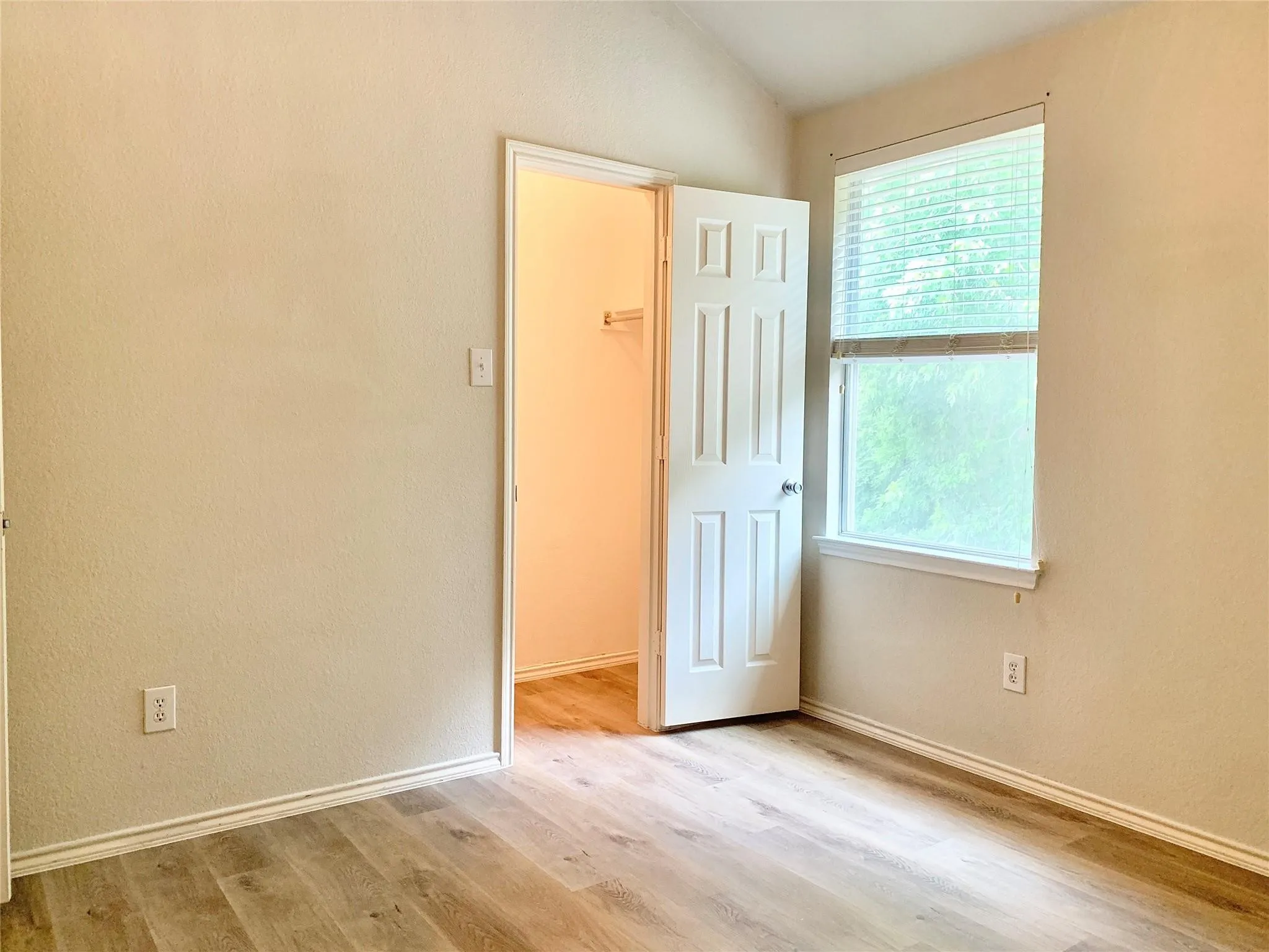 Wood-finish flooring, neutral wall tones, and a window with blinds