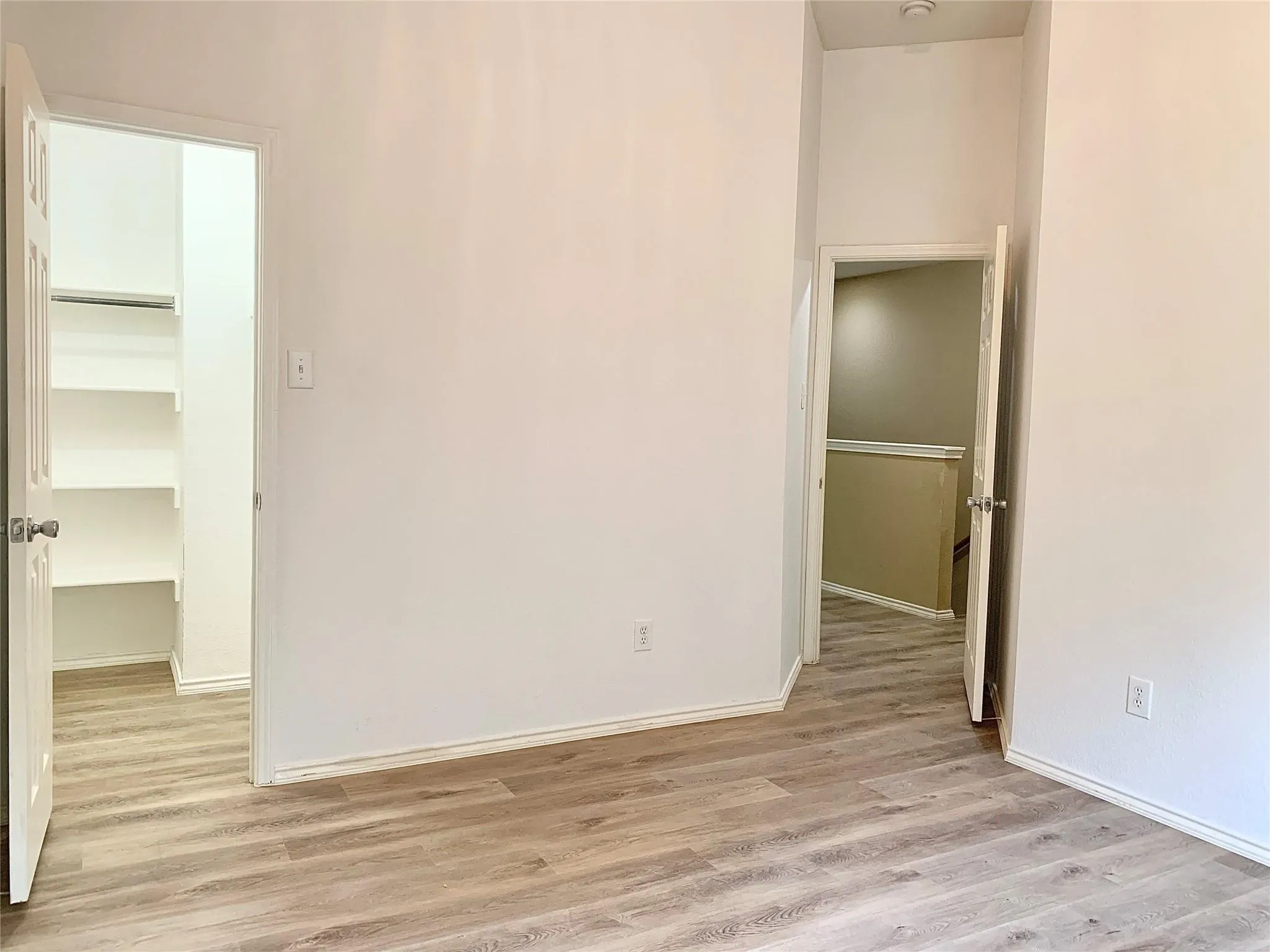Wood-finish flooring throughout, bright white walls, and built-in shelving