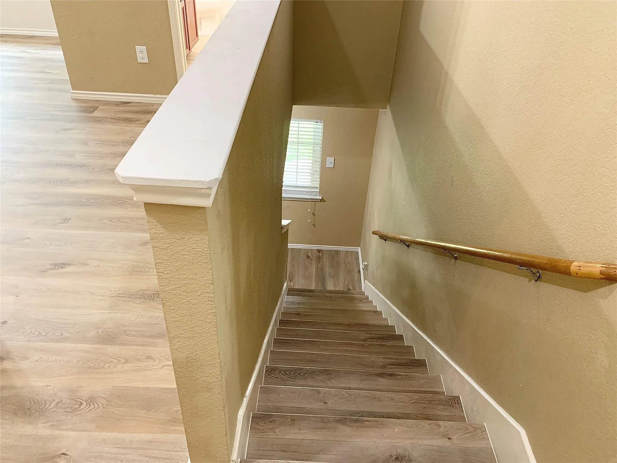 Staircase featuring wood-finish treads, wood-finish flooring, and a handrail