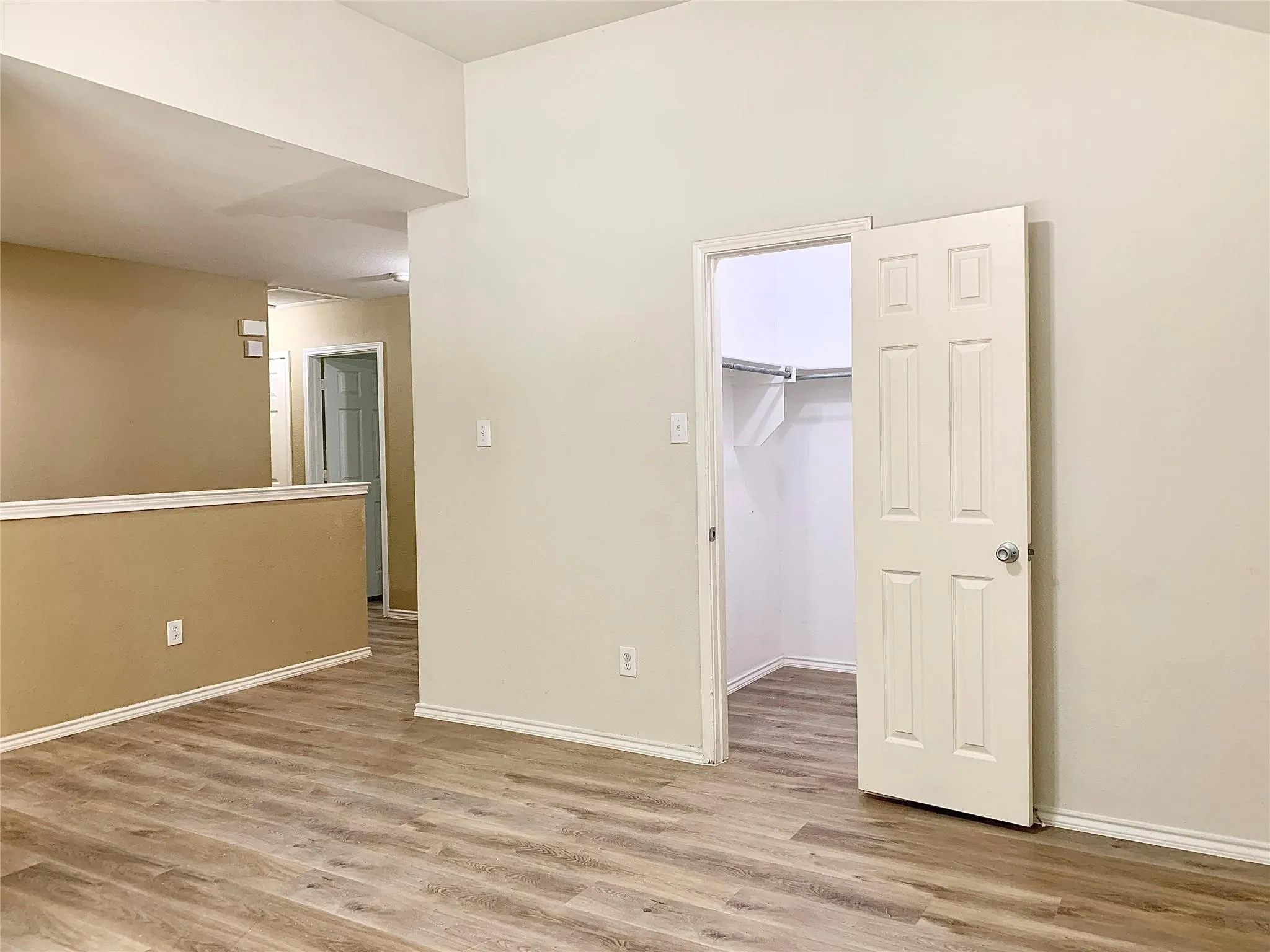 Wood-finish flooring throughout, vaulted ceiling, built-in closet shelving, and a half-wall partition