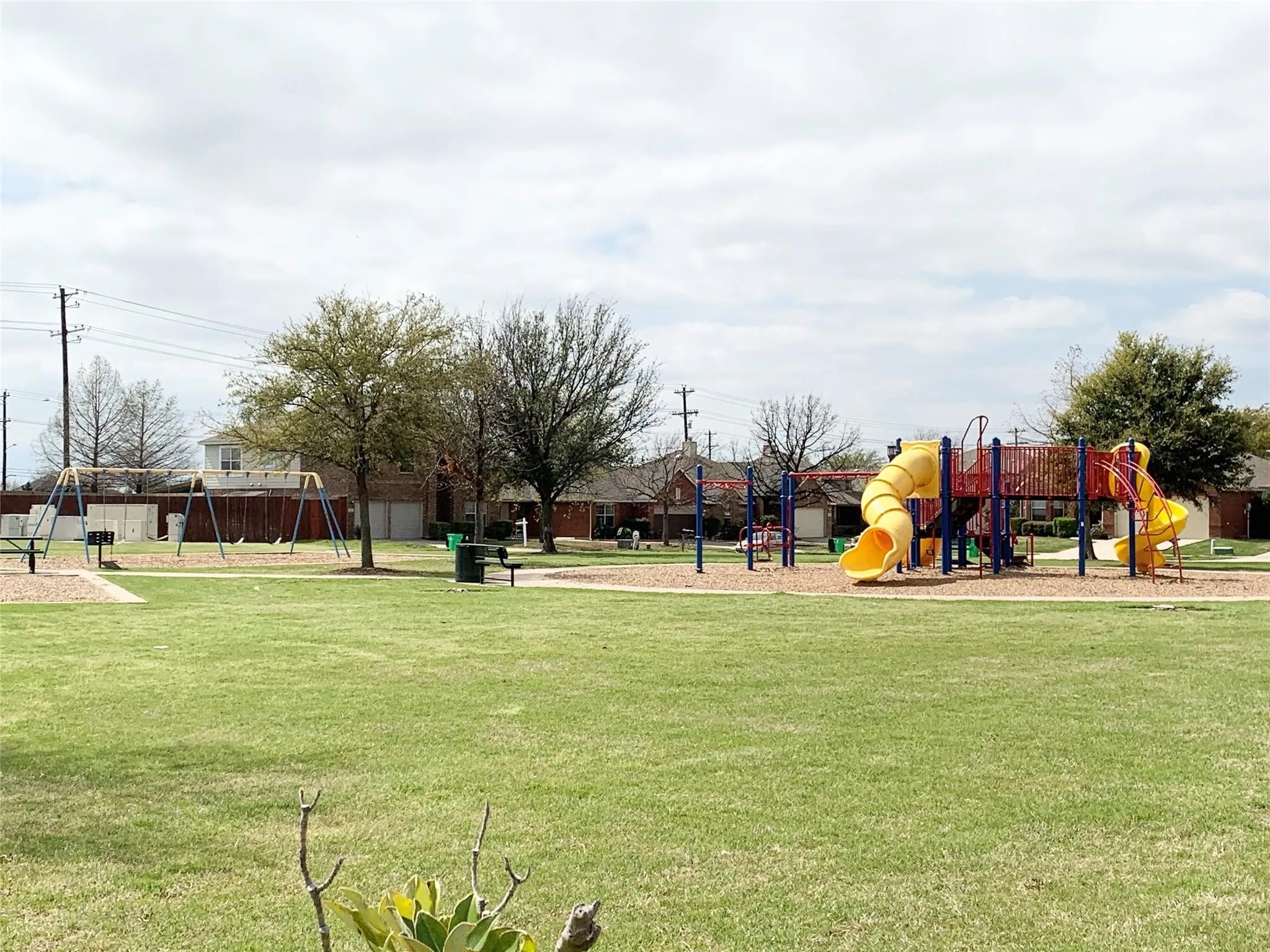 Expansive green space featuring playground equipment, swings, and mature trees