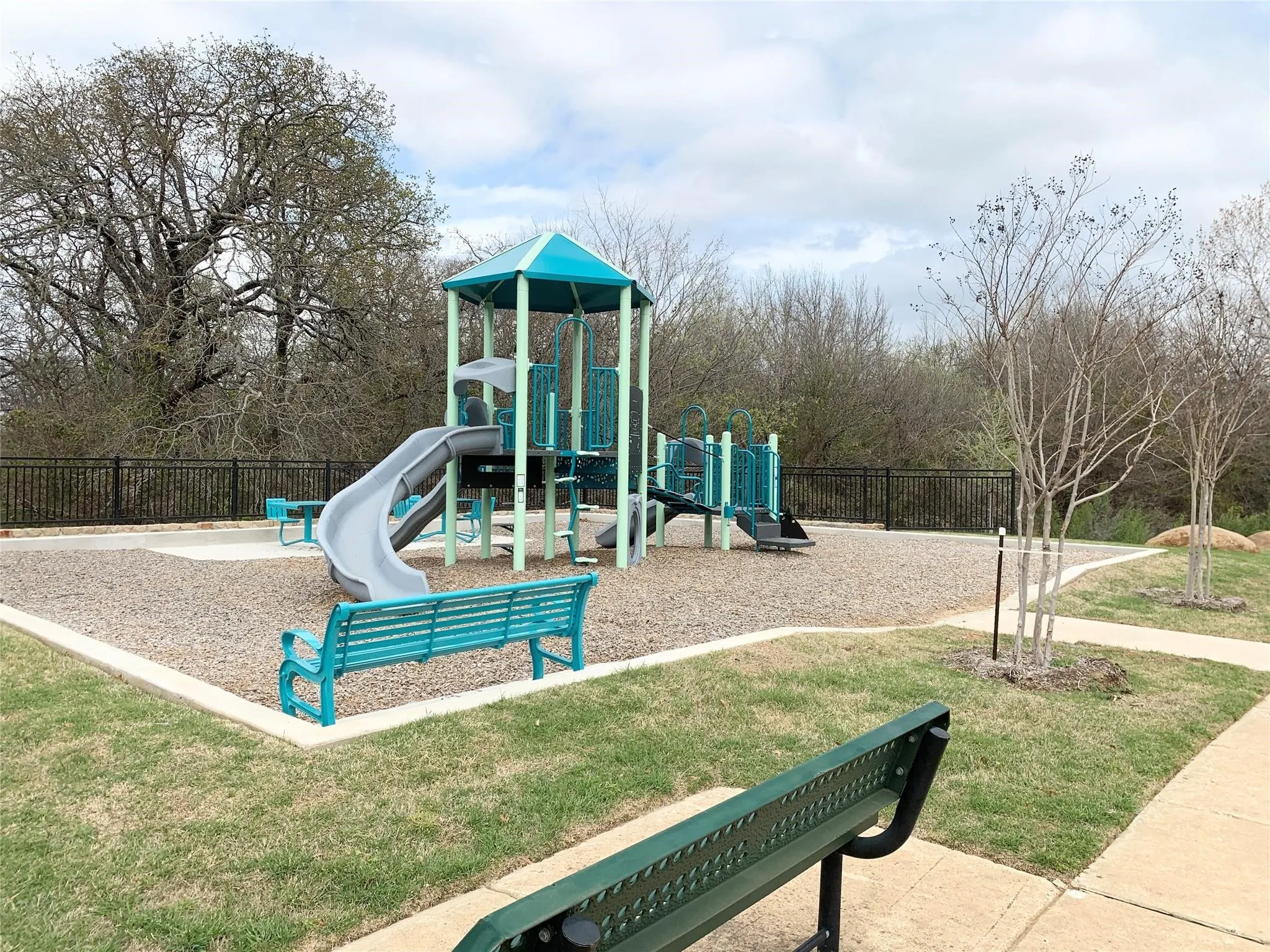Playground area featuring a multi-level play structure, two slides, and two benches