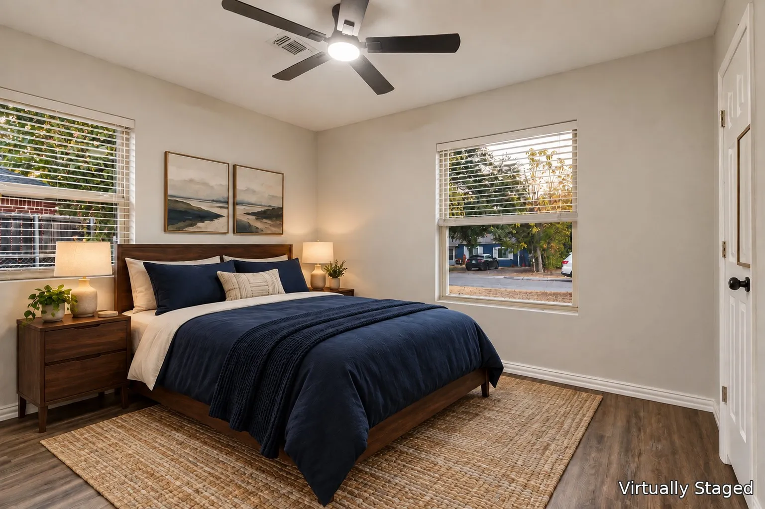Neutral wall tones, wood-finish flooring, two windows with blinds, and a ceiling fan with integrated lighting
