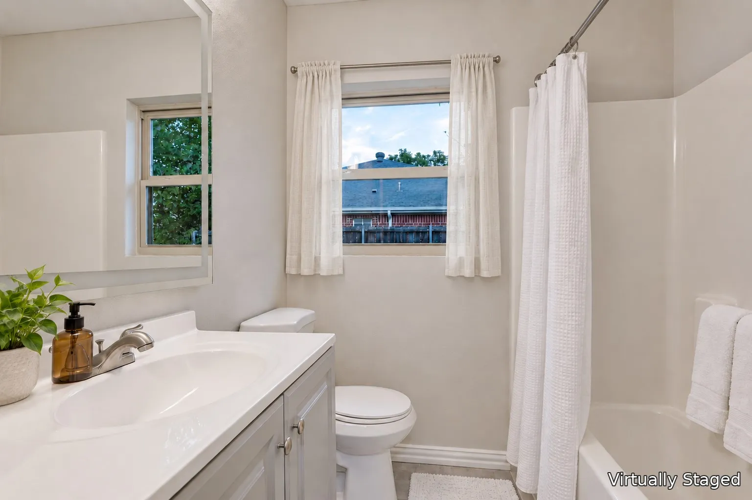 Bathroom featuring a gray vanity with a white countertop, an undermount sink, a toilet, and a bathtub with a shower