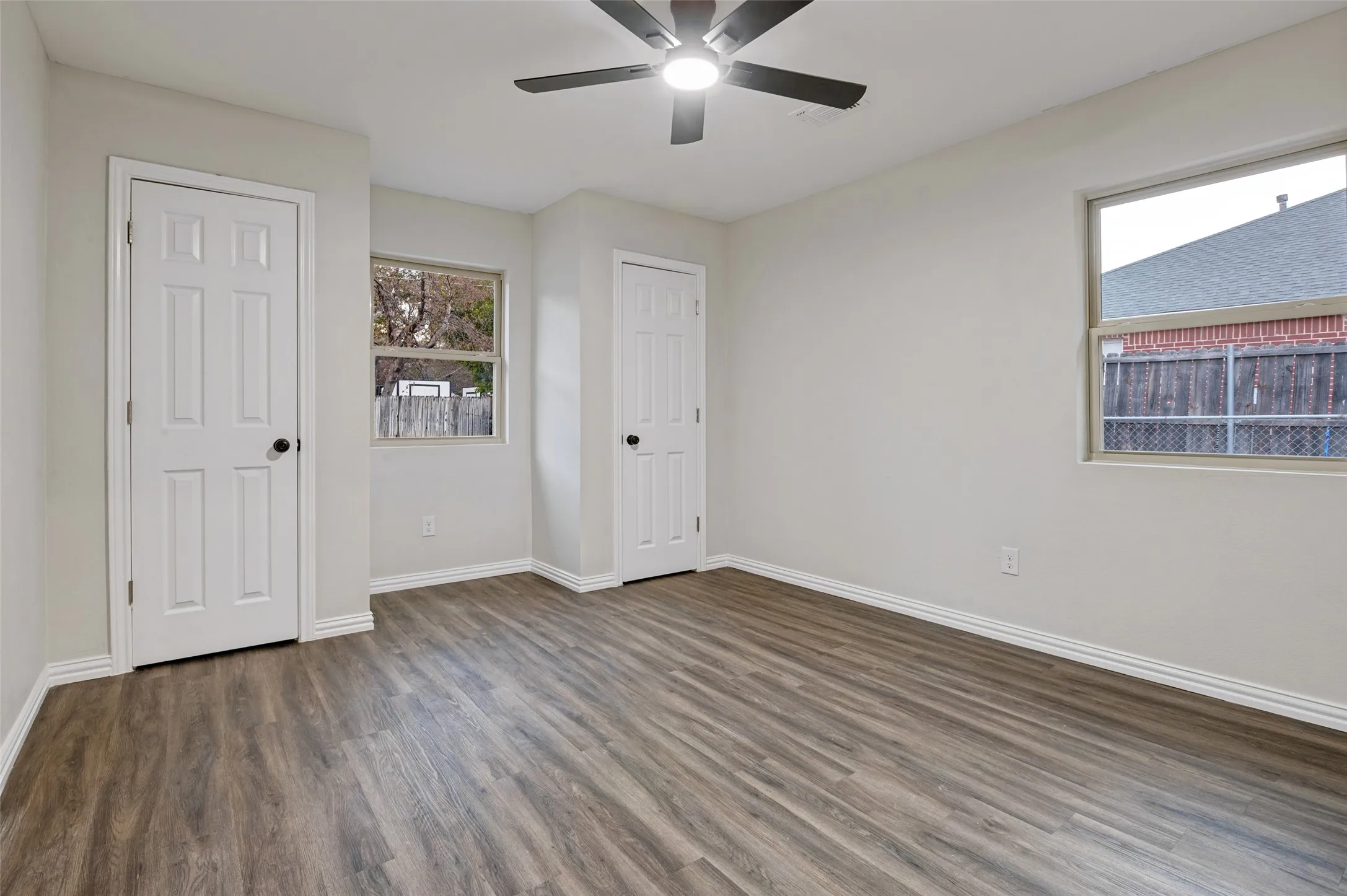 Room featuring wood-finish flooring, white walls, and a ceiling fan