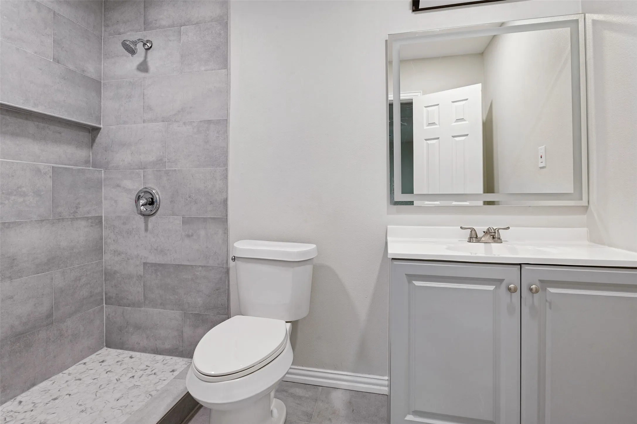Tiled shower with a built-in niche, pebble-style shower floor, and a chrome shower fixture