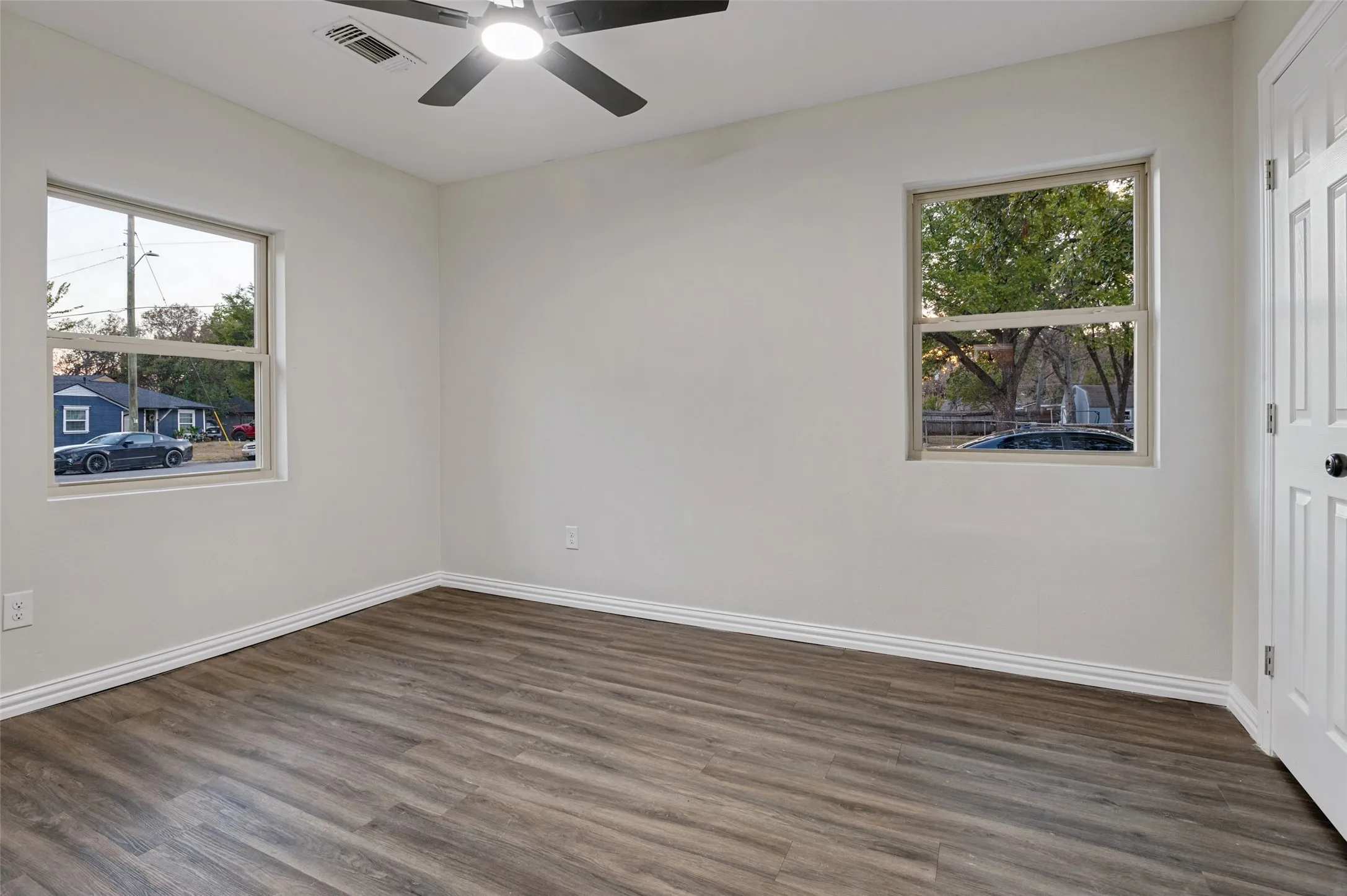 Wood-finish flooring, white walls, and a ceiling fan with integrated lighting