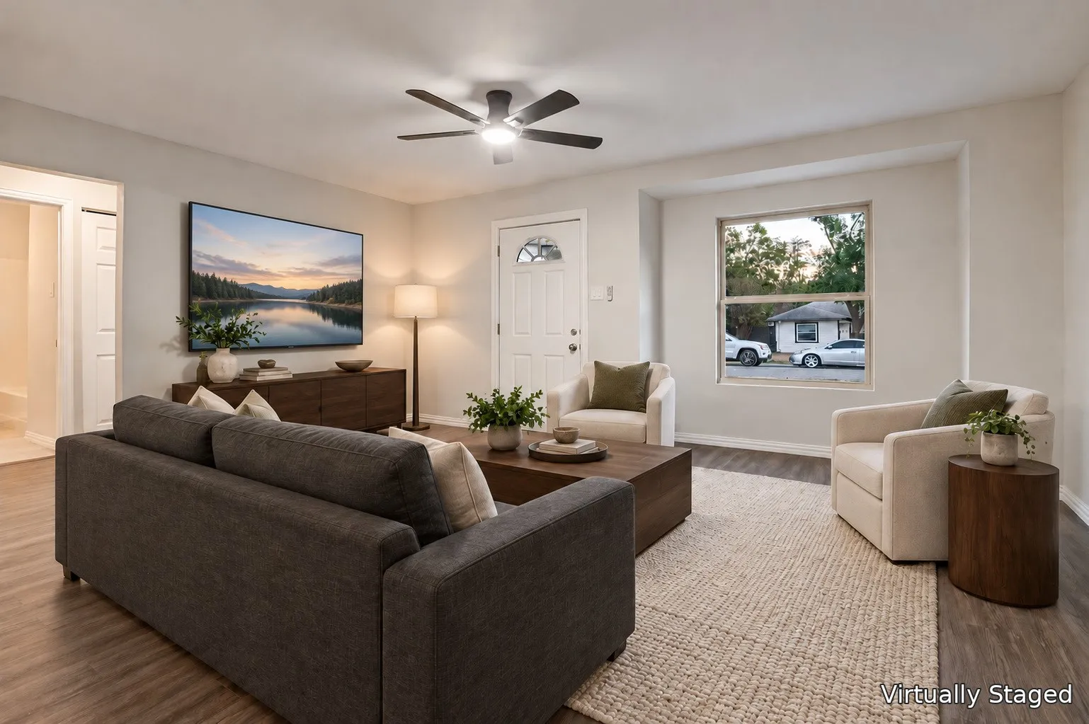 Spacious room with wood-finish flooring, a ceiling fan with integrated lighting, and neutral wall tones