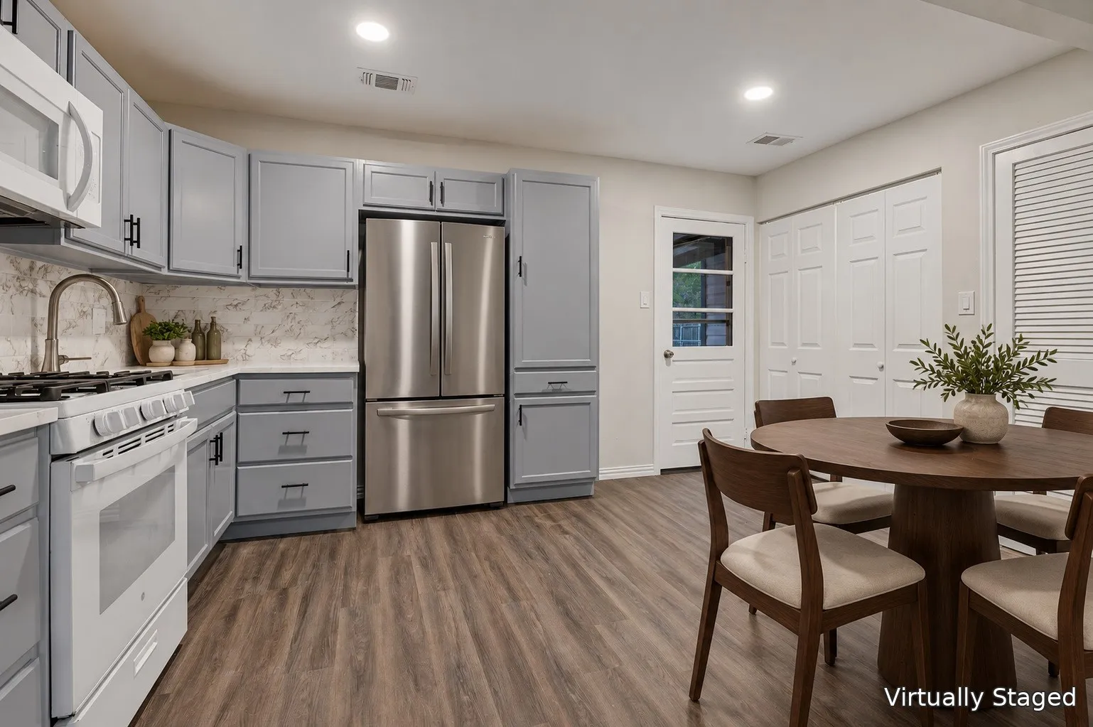 Kitchen featuring gray cabinetry with black hardware, white countertop surfaces, white subway tile backsplash, and wood-finish flooring